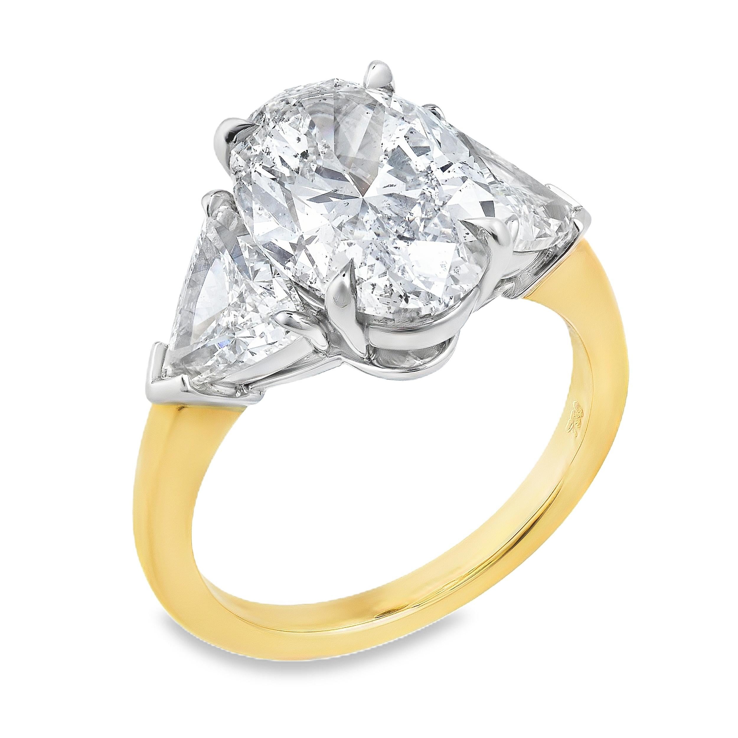 Uno splendido anello di fidanzamento con un diamante di taglio ovale da 4,09 carati certificato da GIA con colore J e purezza I1 e incastonato in una montatura a quattro punte. Affiancato da due diamanti taglio trilione per un peso totale di 1,59