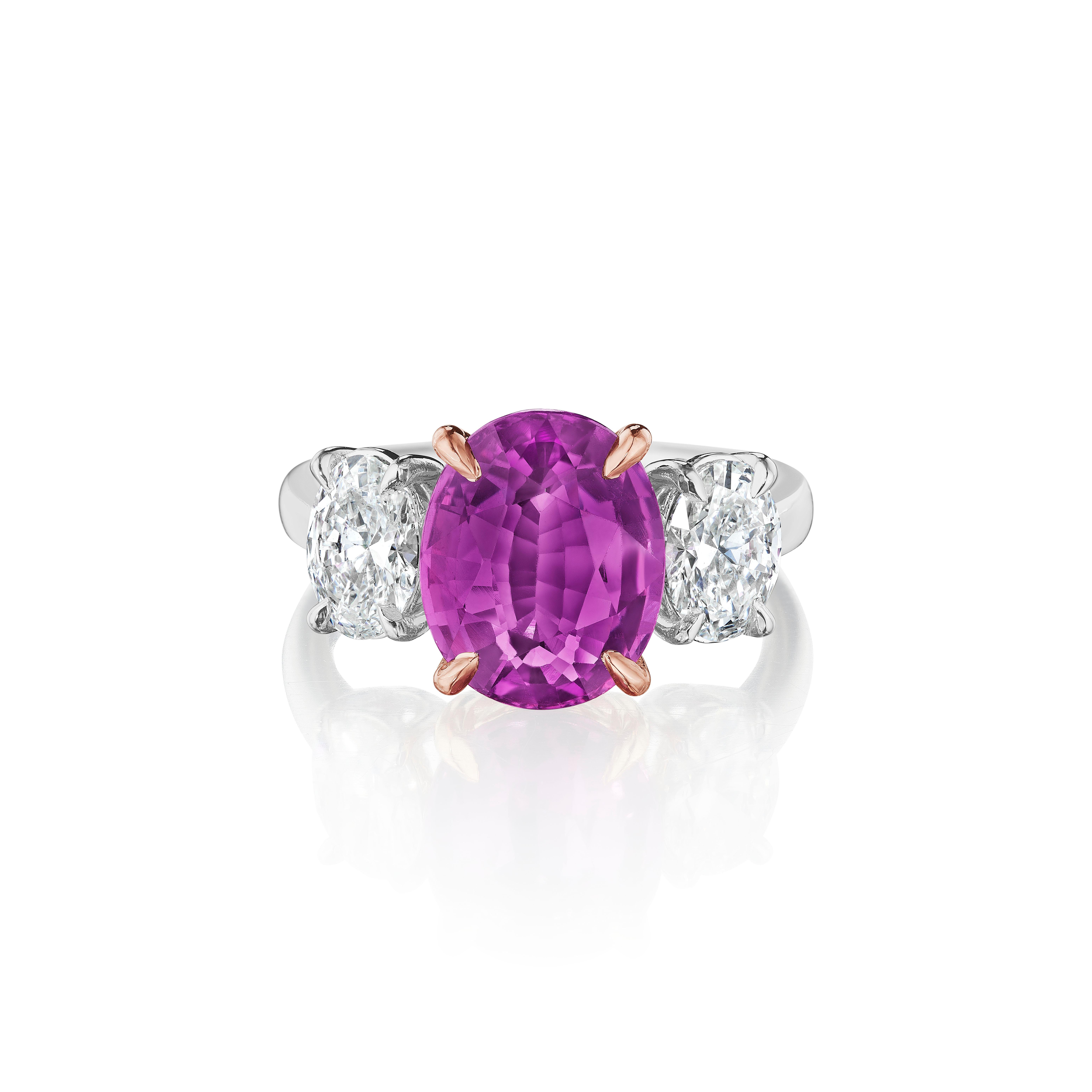 Un zafiro rosa único de talla ovalada con un ligero toque púrpura, un color poco frecuente, de 4,09 quilates. Certificado por GIA como calentado. 
Flanqueada por diamantes de talla ovalada con un peso total de 1,23 quilates. Cada una certificada por