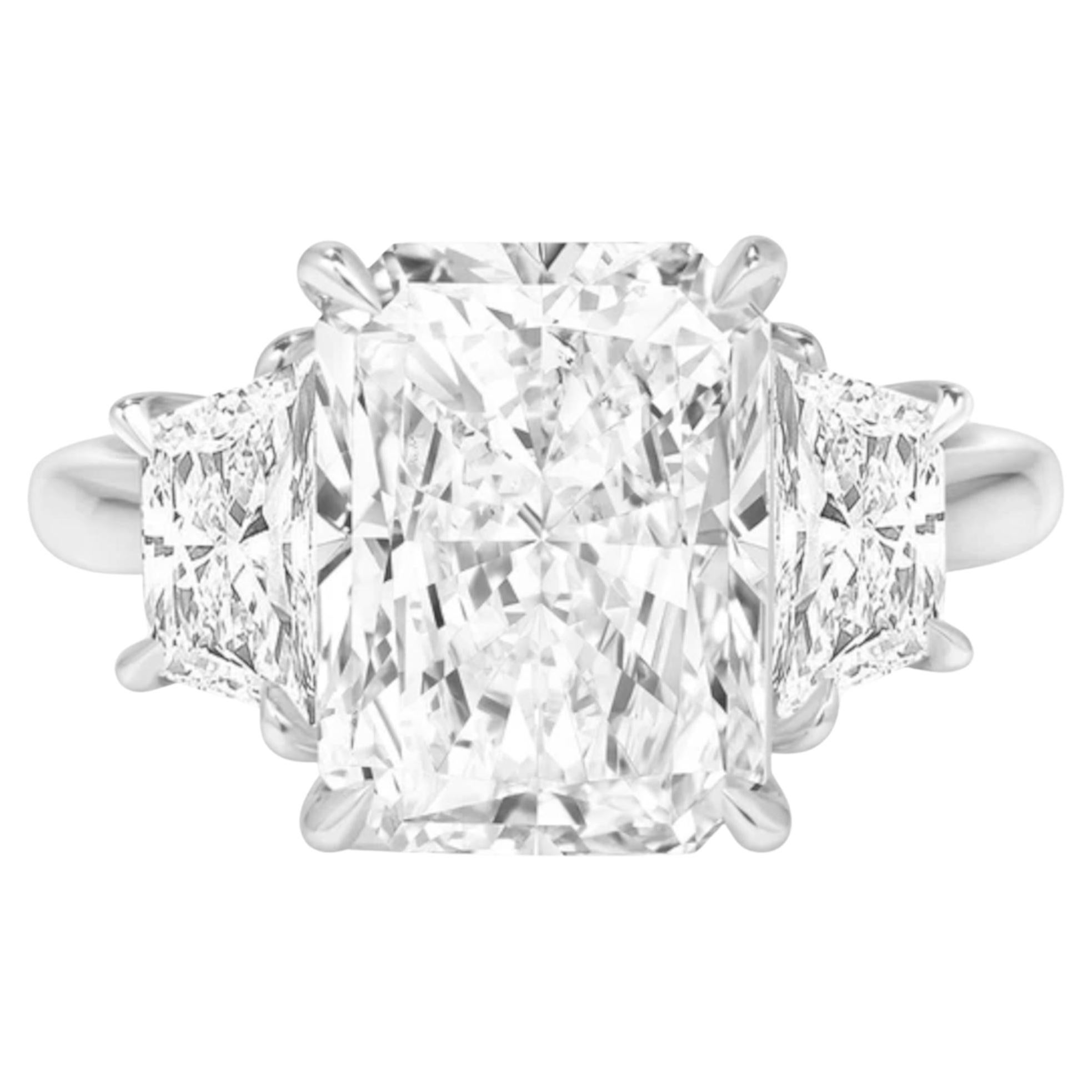 This engagement ring is a stunning masterpiece of elegance and sophistication. At its center is a 4.01 carat radiant cut diamond, certified by GIA for its exceptional quality. Complementing the center stone are two trapezoid-shaped diamonds,