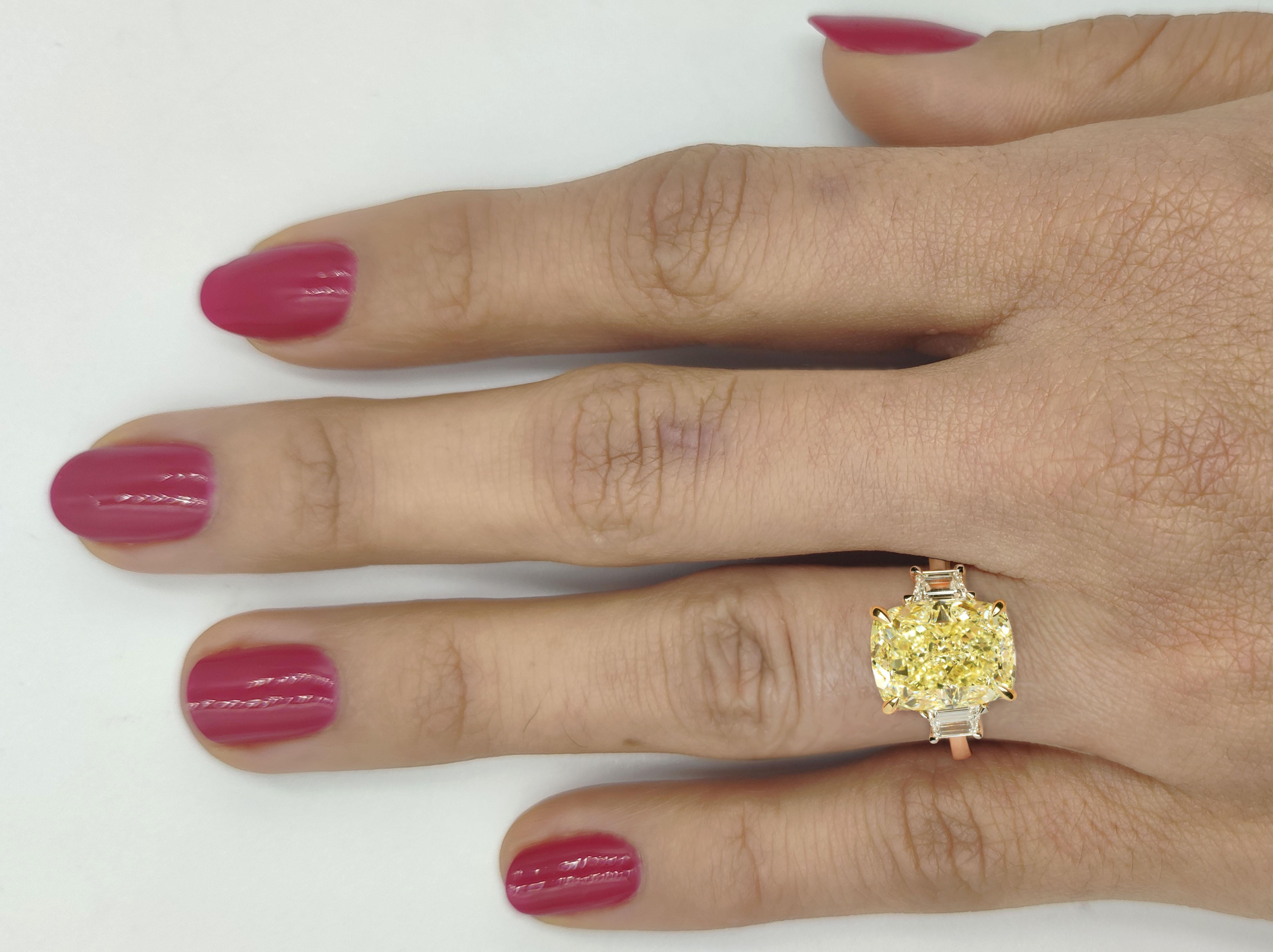 Cette captivante bague de fiançailles met en valeur un diamant jaune fantaisie de 4.12 carats à taille coussin, certifié par le GIA, qui constitue son point focal lumineux. La pierre centrale vibrante est maintenue par une monture en or jaune 18