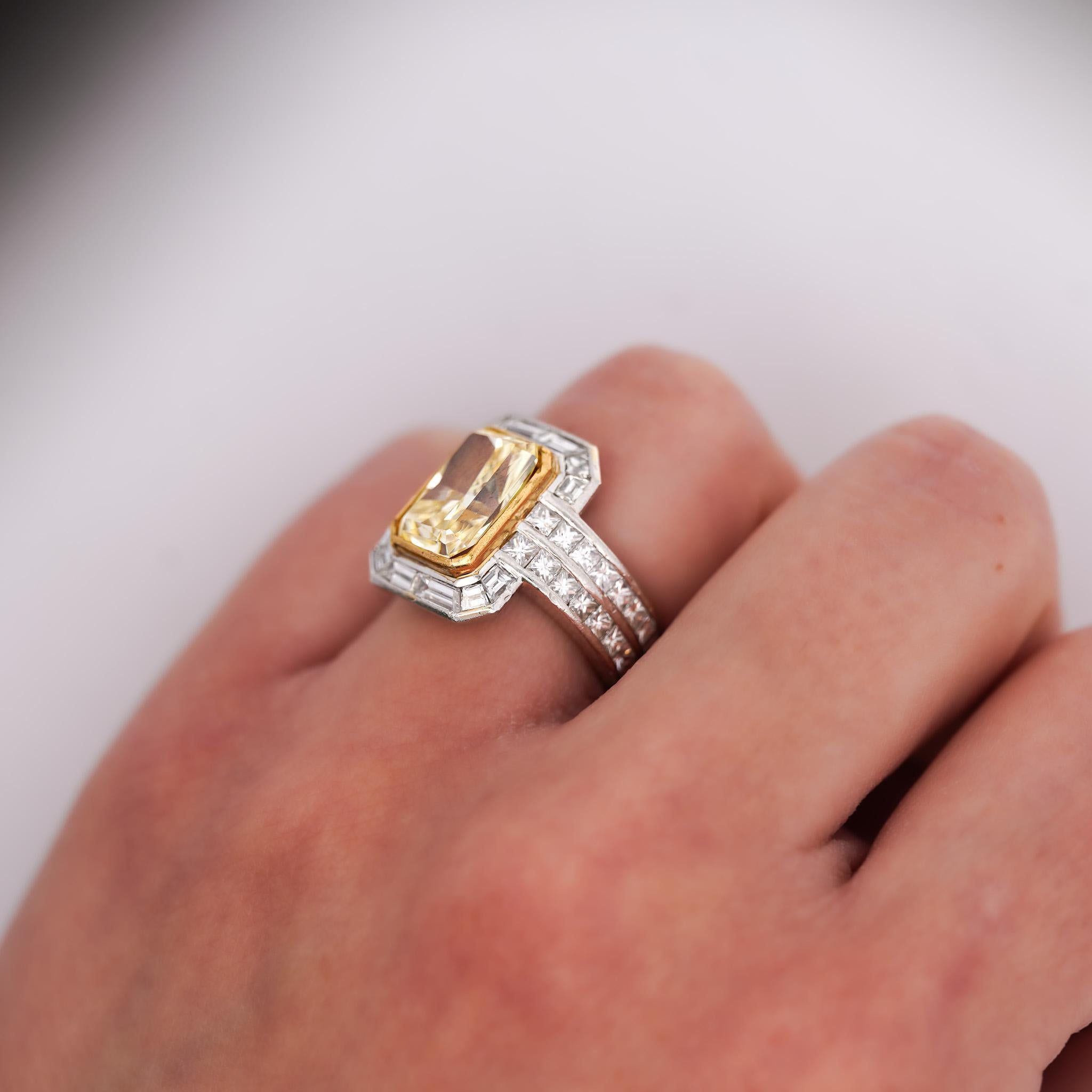 Diamant jaune radiant certifié GIA de 4,12 carats en or blanc 18 carats, serti clos d'inspiration Art déco avec halo en diamant baguette et épaulements en diamant baguette à double rangée.

Bague de taille 4,5 réglable, pesant 13,3