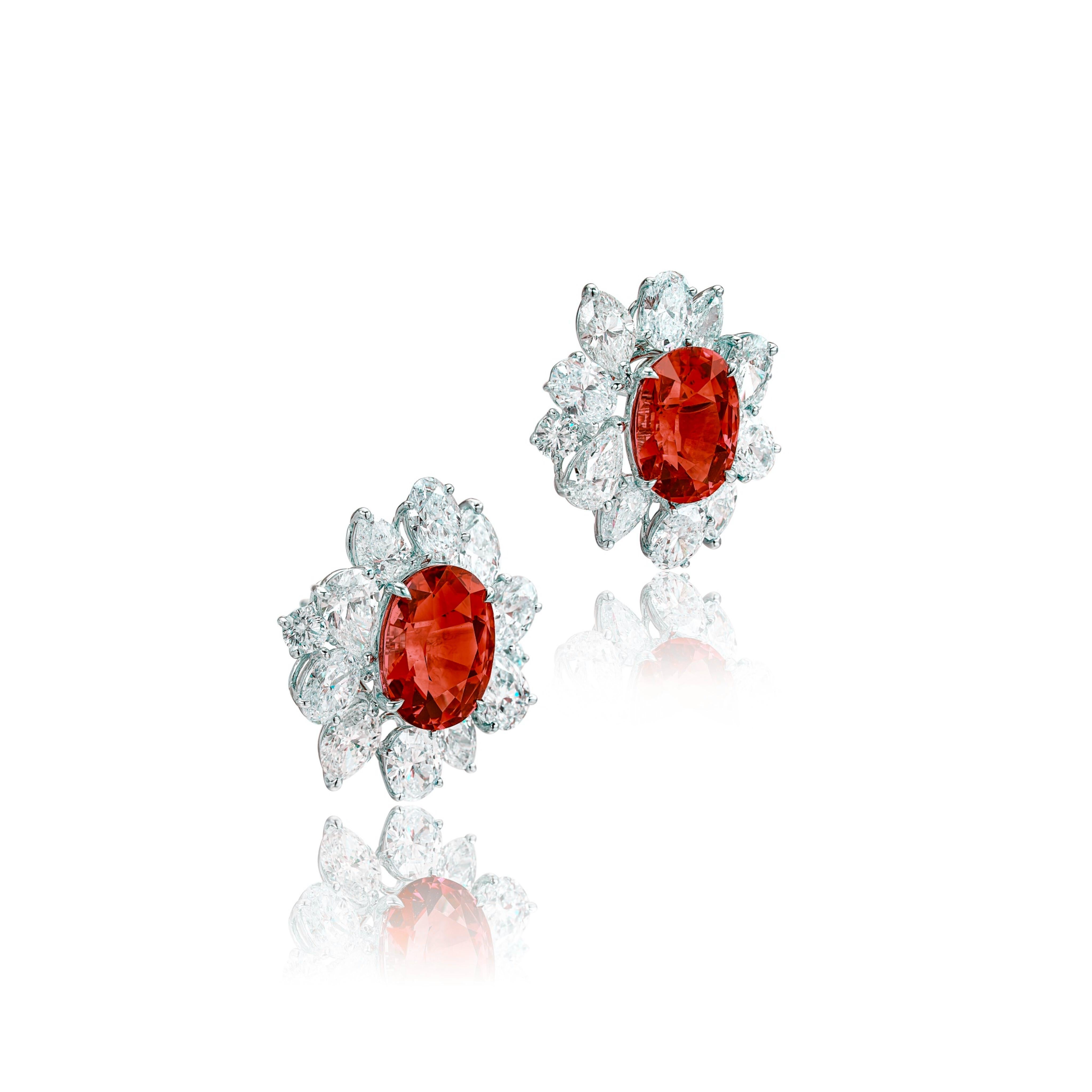 an exquisite pair of earrings featuring a stunning oval rubies at their center, surrounded by a dazzling array of marquise and pear-shaped diamonds. Crafted in luxurious 18 karat white gold, this elegant pair offers a perfect blend of vibrant color