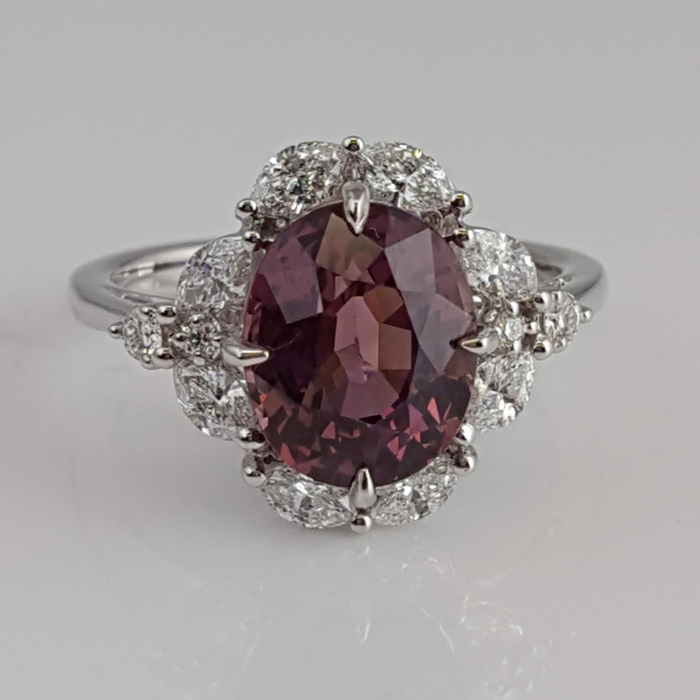 (DiamondTown) With a GIA Certified 4.19 carat oval cut exotic garnet center, set inside a halo of marquise cut white diamonds (total diamond weight 0.68 carats), this ring shines from every angle.

GIA Certification details (see photo):
The center