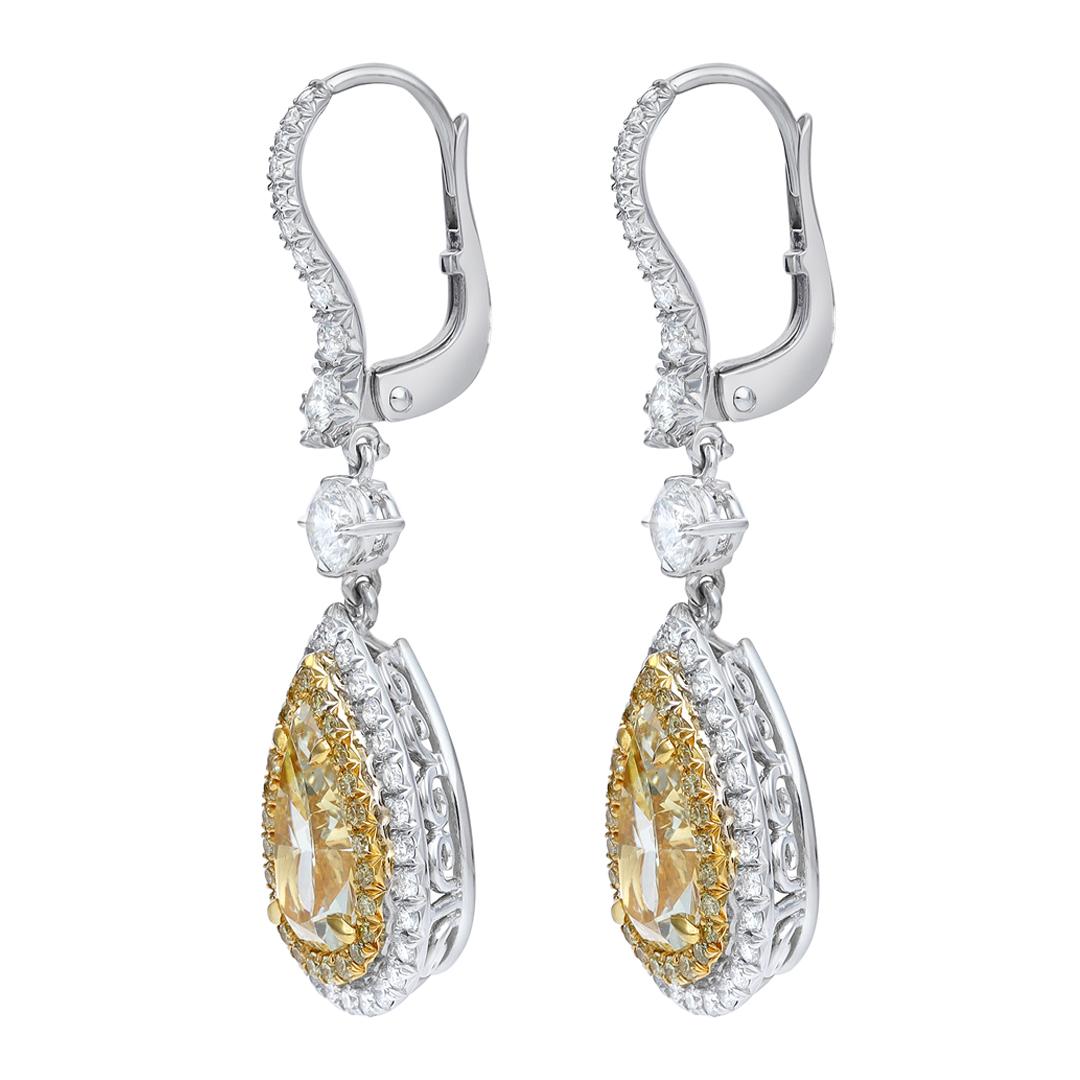 A gorgeous pair of dangle earrings, showcasing two pear shape yellow diamonds weighing 2.13 and 2.06 carats, each set on a four prong setting made of 18K yellow gold. Surrounded by an inner halo of round cut yellow diamonds weighing 0.36 carat total