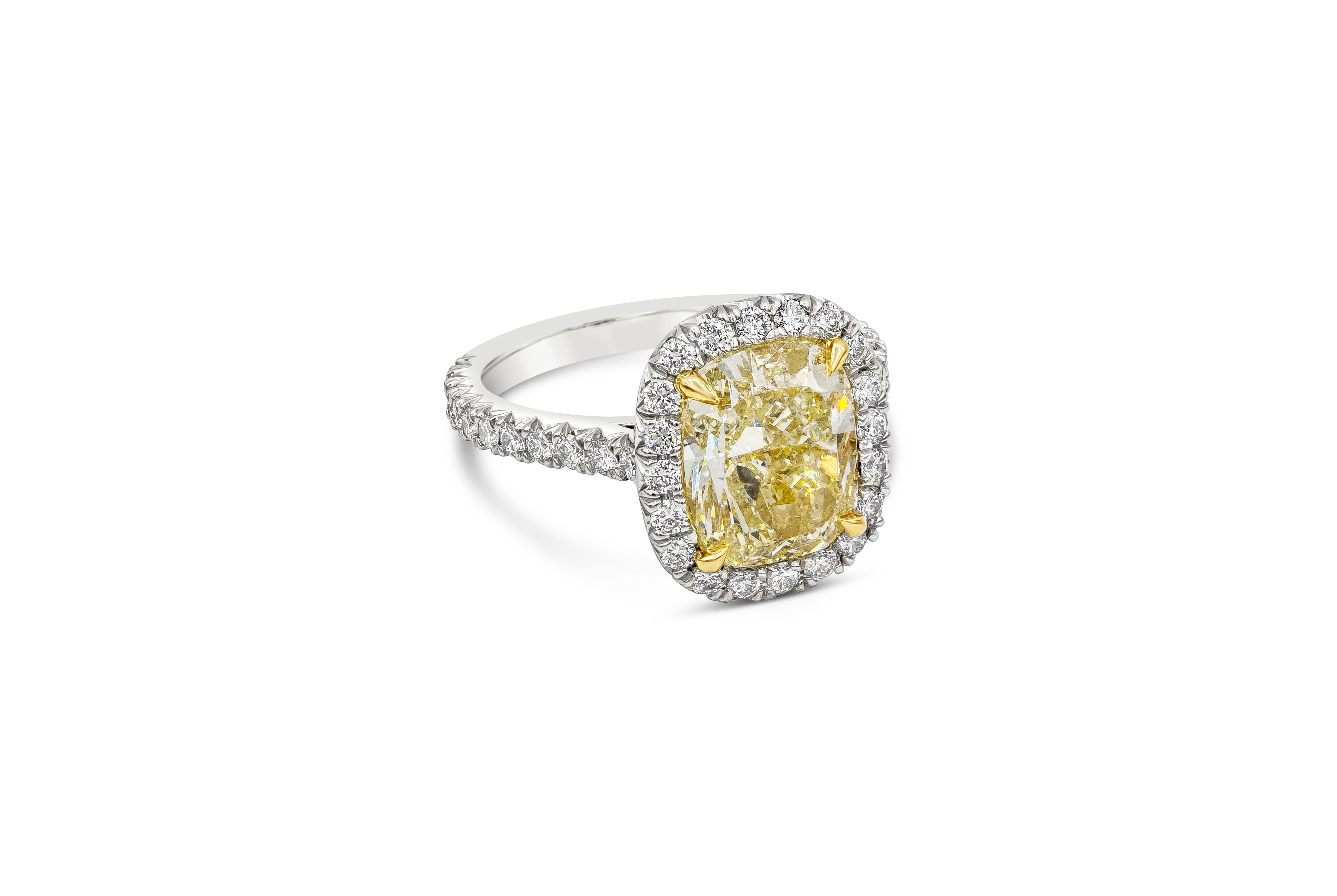 A classic halo engagement ring style showcasing a 4.30 carat cushion cut yellow diamond, certified by GIA as Y-Z color, VS2 clarity. Center diamond is surrounded by a thin a brilliant diamond halo, set in a diamond encrusted mounting. White diamonds