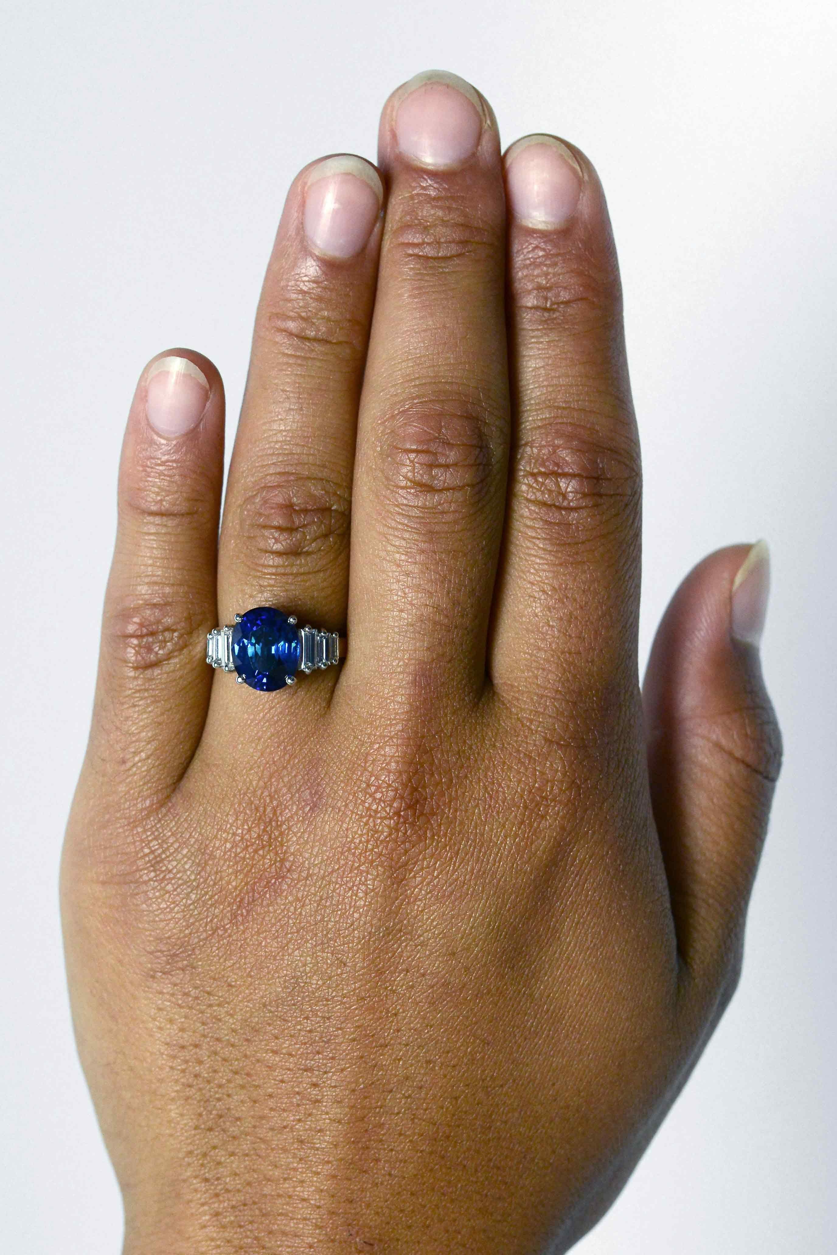 This vivid, natural blue sapphire engagement gemstone ring centers on a captivating, GIA certified 4.39 carat sapphire of a deeply saturated, rich velvety hue. The custom Art Deco style tiered staircase setting is complimented by baguette diamond
