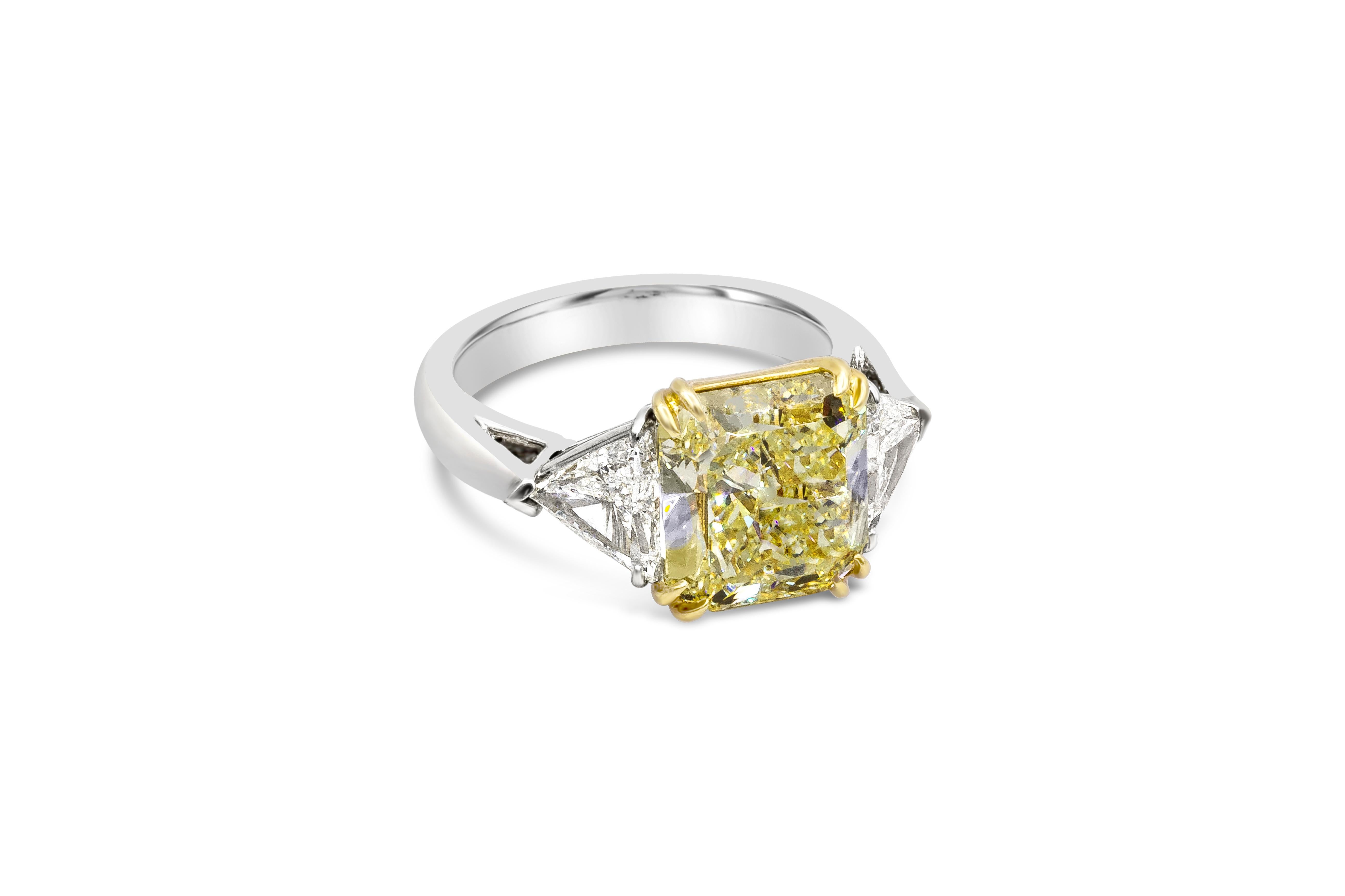 This elegant three-stone engagement ring features 4.50 carat radiant cut yellow diamond, certified by GIA as Fancy Yellow color, VS1 in clarity. Flanking by brilliant trillion cut diamonds weighing 0.99 carat total. Set in a polished platinum