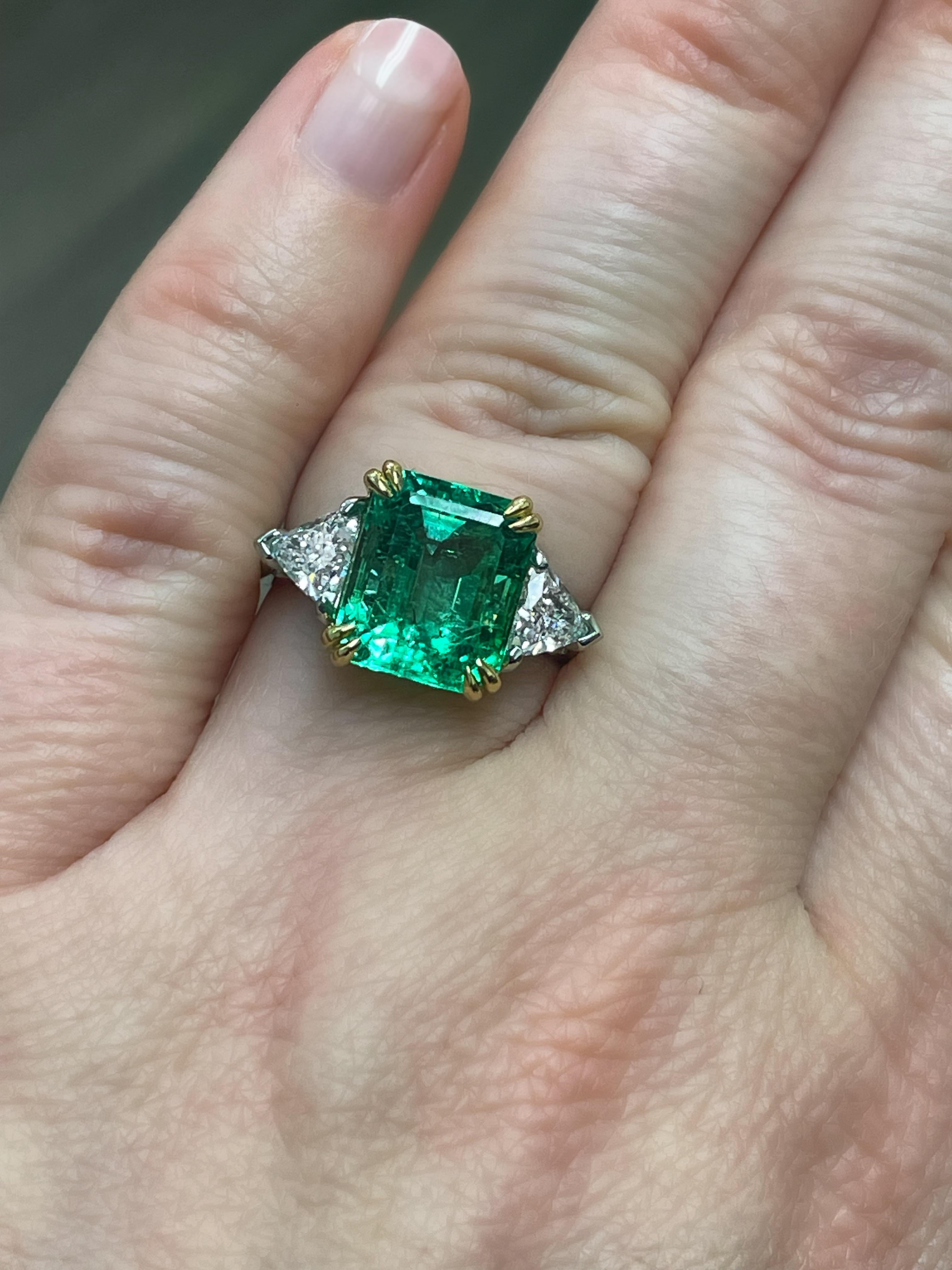 Este anillo absolutamente impresionante ostenta una preciosa esmeralda colombiana de 4,56 quilates, certificada por el GIA con una leve mejora de claridad y que mide 11,03 x 9,30 x 6,55 mm. Flanqueado por dos diamantes talla trillón de primera