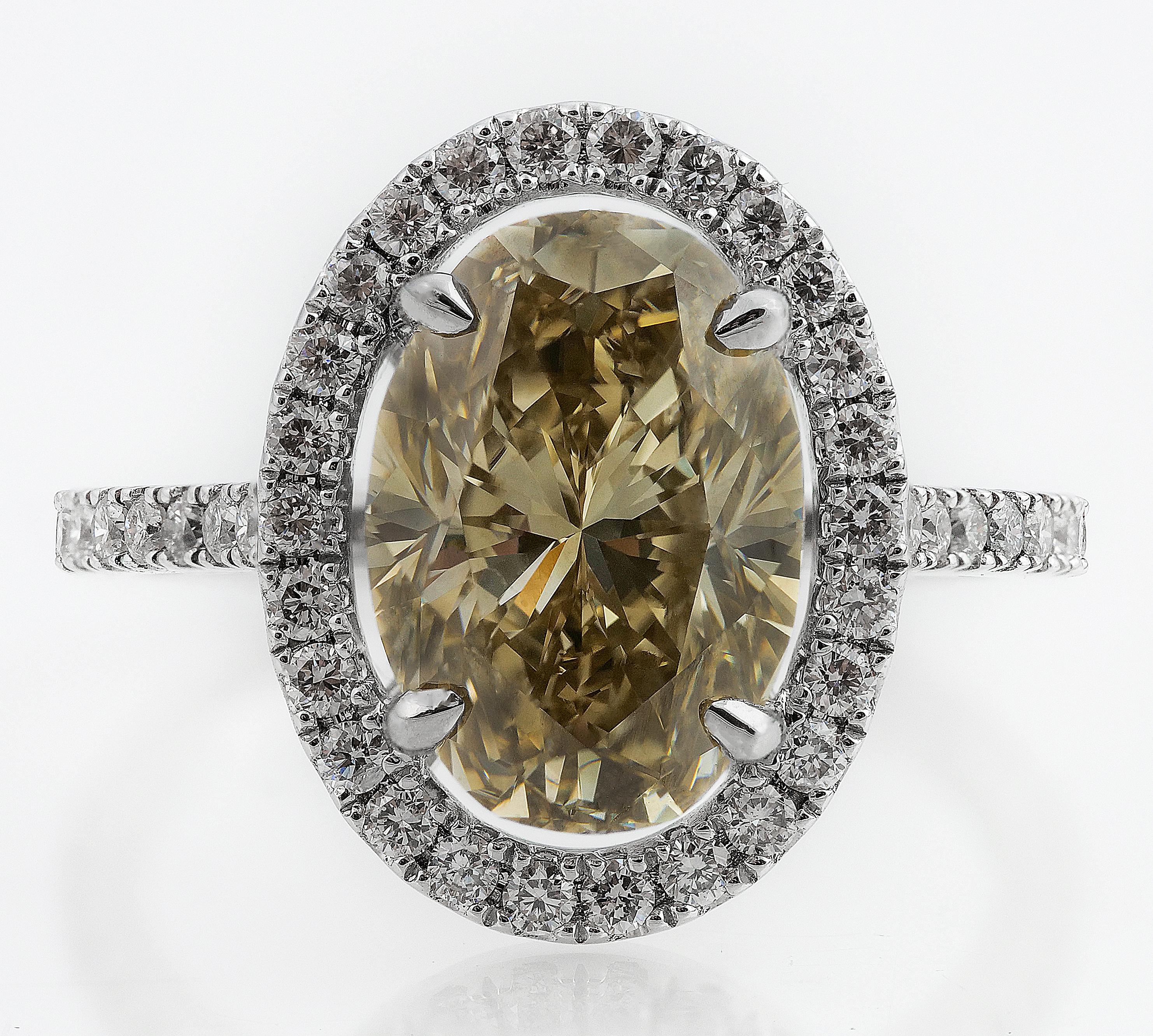 Statement ring consisting of a fancy brownish greenish-yellow colour, natural untreated diamond center and surrounded by glistening round brilliant cut diamonds and diamond shoulders, set on an 18 ct white gold. The beautiful contrast between the