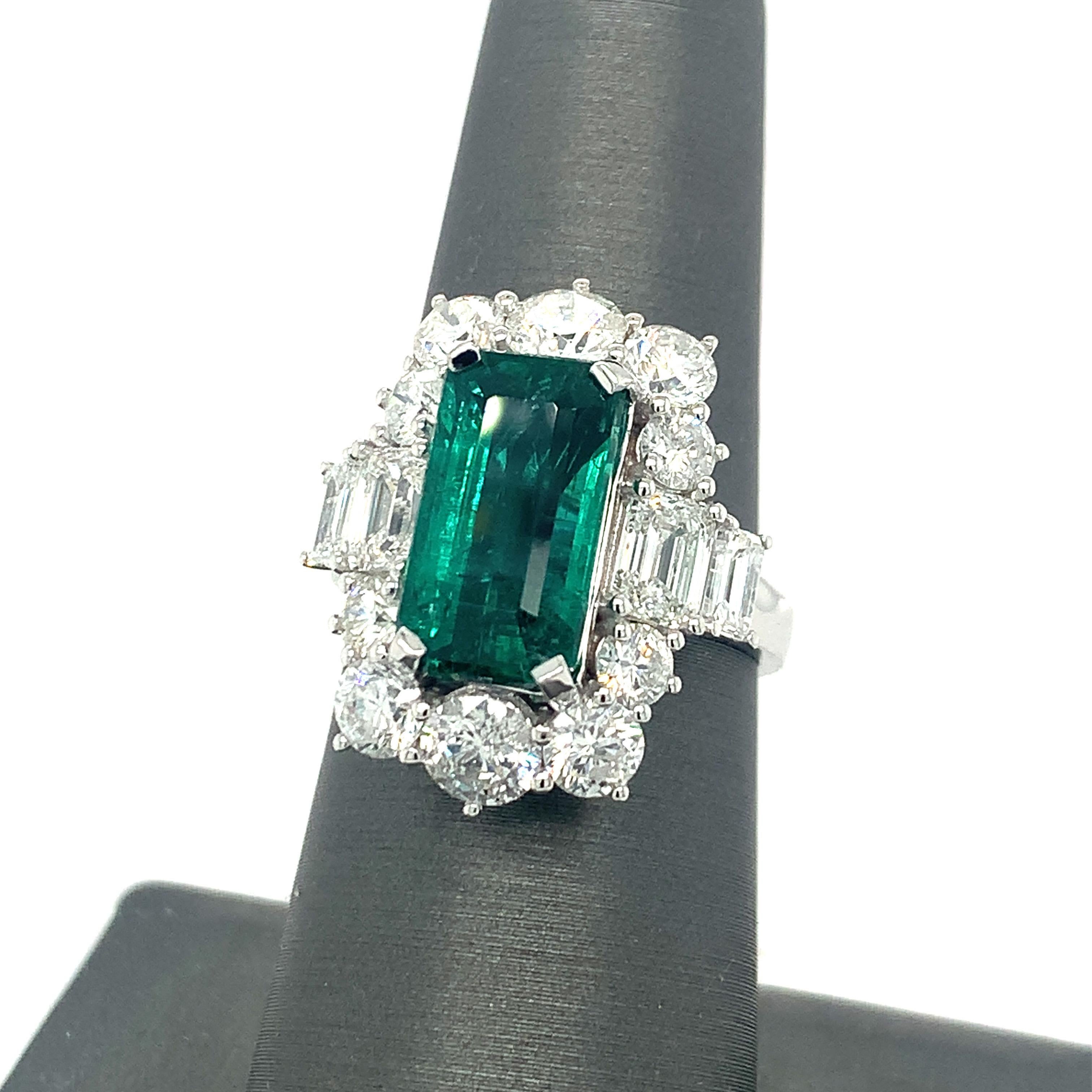 This exceptional creation, Emerald ring has an array of ten brilliant cut diamonds surrounding the center stone and four additional emerald cut diamonds on the sides. The center stone, Emerald cut Emerald, is GIA certified and also the Emerald cut