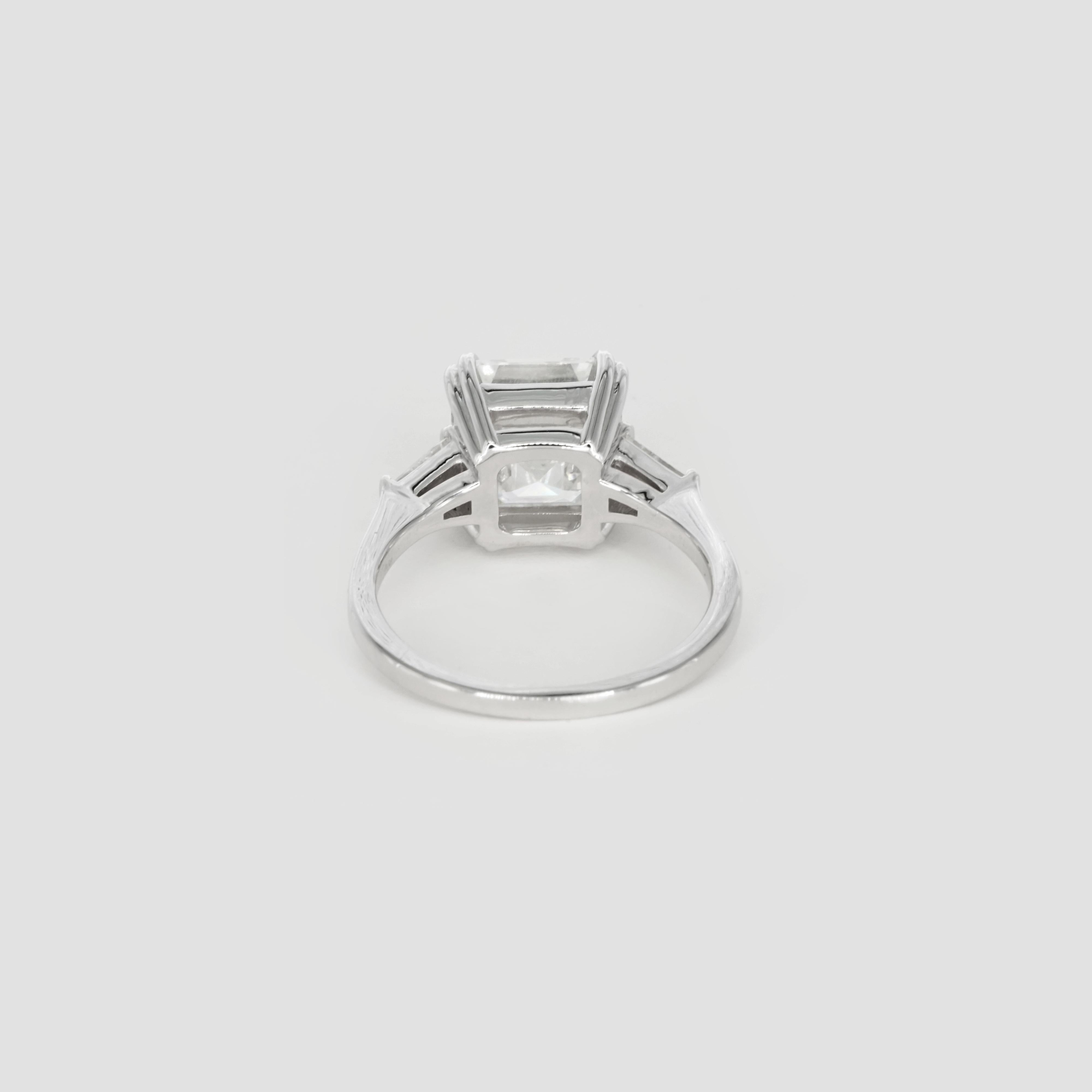 This stunning Cecile Blake creation features a mesmerizing 5-carat Asscher-cut diamond as the centerpiece, showcasing its exceptional clarity, symmetry, and timeless elegance. The diamond's step-cut facets create a captivating hall-of-mirrors