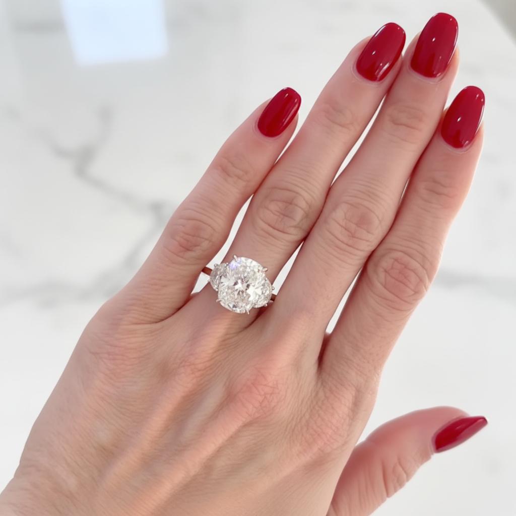 Magnifique bague à trois pierres centrée sur un exceptionnel diamant Brilliante modifié coussin de 5,01 carats certifié par le GIA, de couleur H et de pureté VS1. Les proportions du diamant (11,04 x 9,24 x 6,41 mm) lui confèrent une présence et une