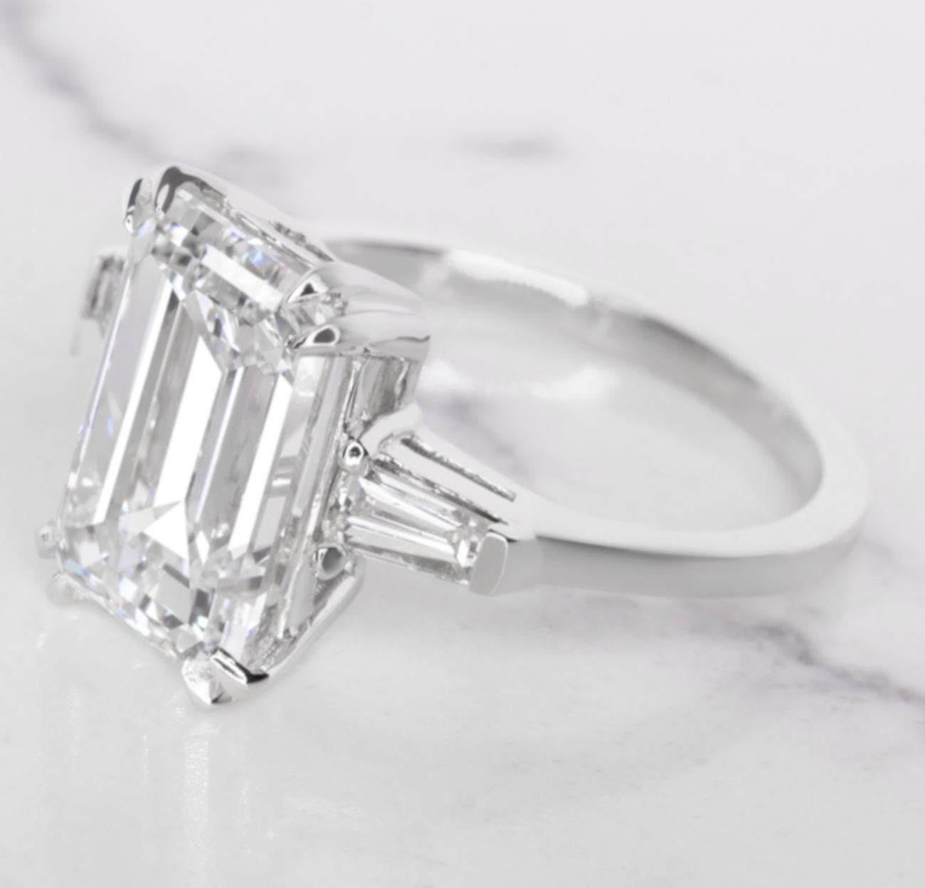 Indulge in the allure of sophistication with this captivating ring, where a magnificent 5-carat emerald-cut diamond takes center stage. The G color and VVS2 clarity of the diamond contribute to its exceptional brilliance and purity, making it a