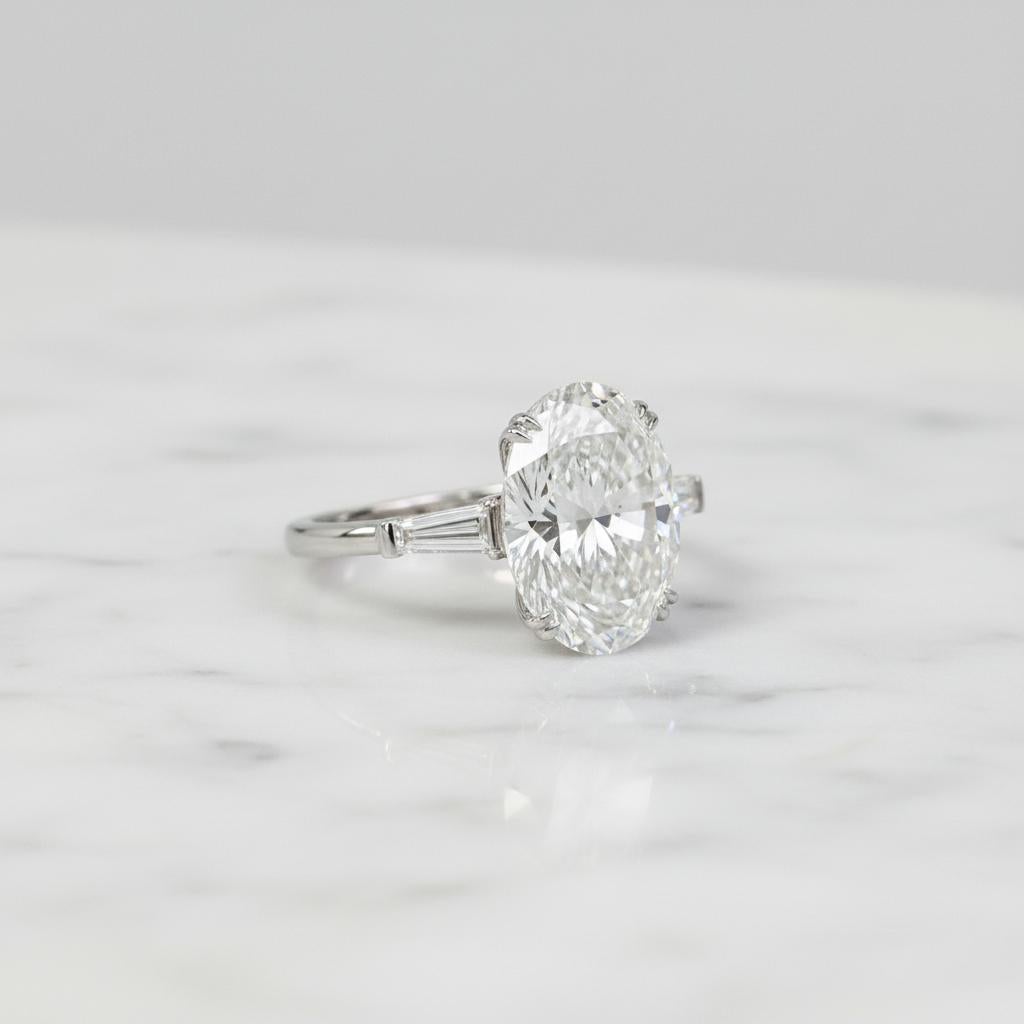 An engagement ring of timeless sophistication, this piece is centered around a breathtaking 5.01 carat Oval Brilliant Cut Diamond that has been certified by GIA as E color and VS1 clarity. Exceptional in both quality and beauty, the diamond displays