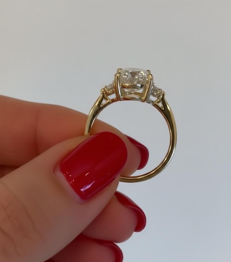 Questo eccezionale anello di fidanzamento a tre pietre presenta un magnifico diamante ovale taglio brillante da 5 carati certificato GIA di colore E e purezza VS2. Il centro è elegantemente affiancato da due diamanti taglio Cadillac perfettamente