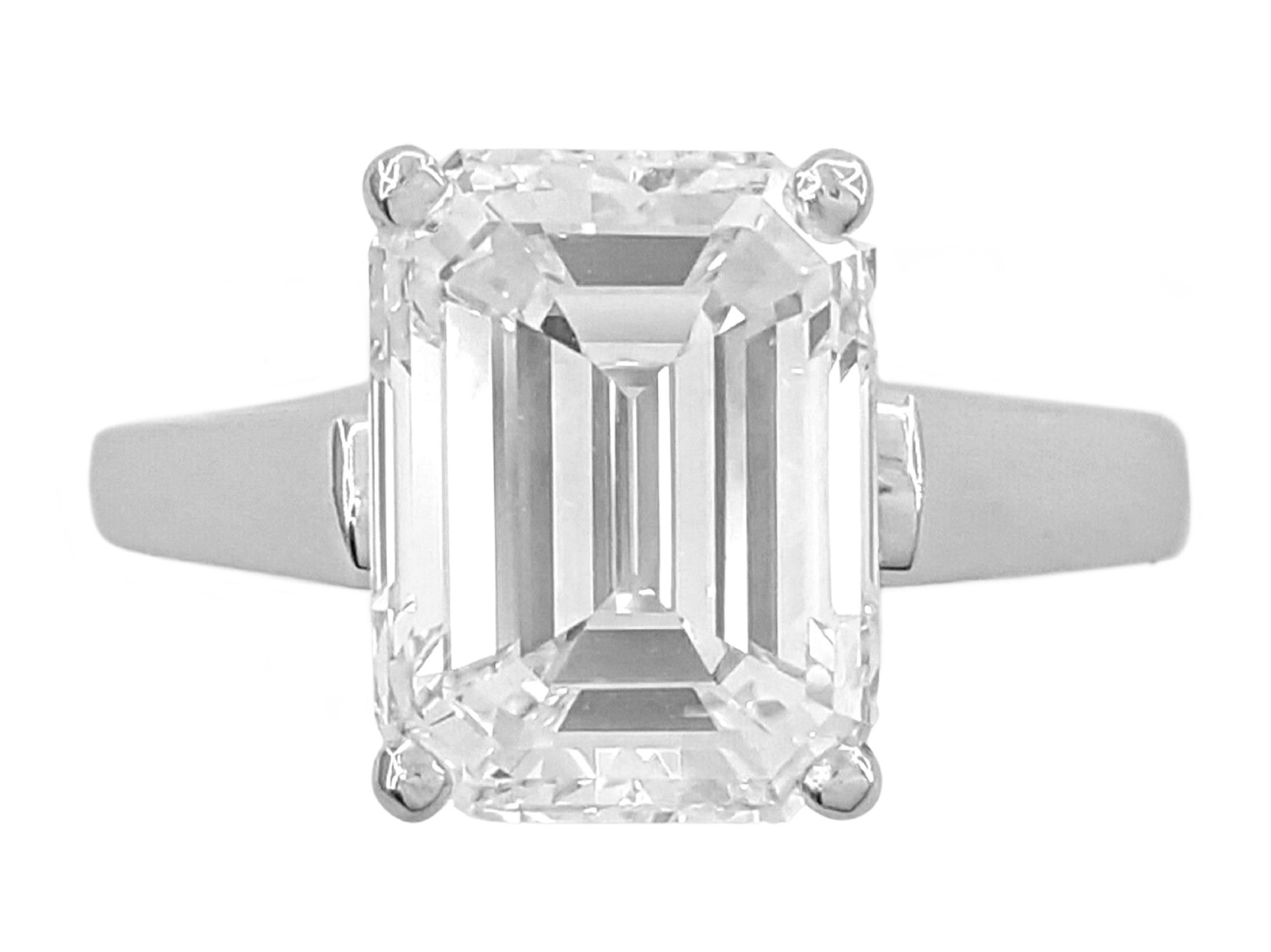 This exquisite solitaire engagement ring features a GIA certified 5.08 carat emerald-cut diamond set in a polished platinum band. 

The diamond boasts an E color grade, offering near-colorless brilliance that enhances its remarkable clarity. With an