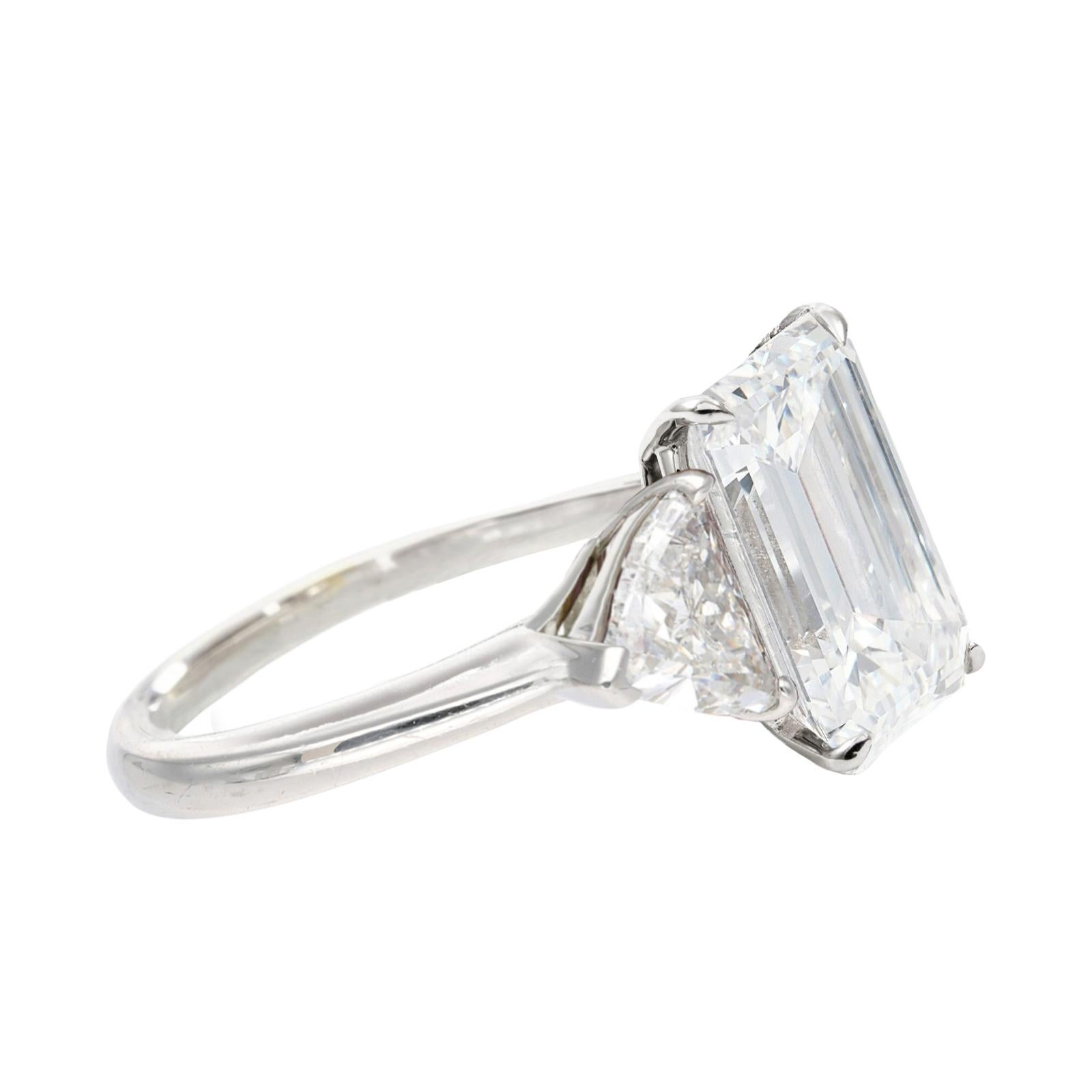 Presenting a breathtaking GIA Certified 5.52 carat emerald cut diamond ring, elegantly set in platinum with trillion cut diamonds on either side. 

The centerpiece diamond showcases a rare and coveted E color grade, signifying it's exceptional