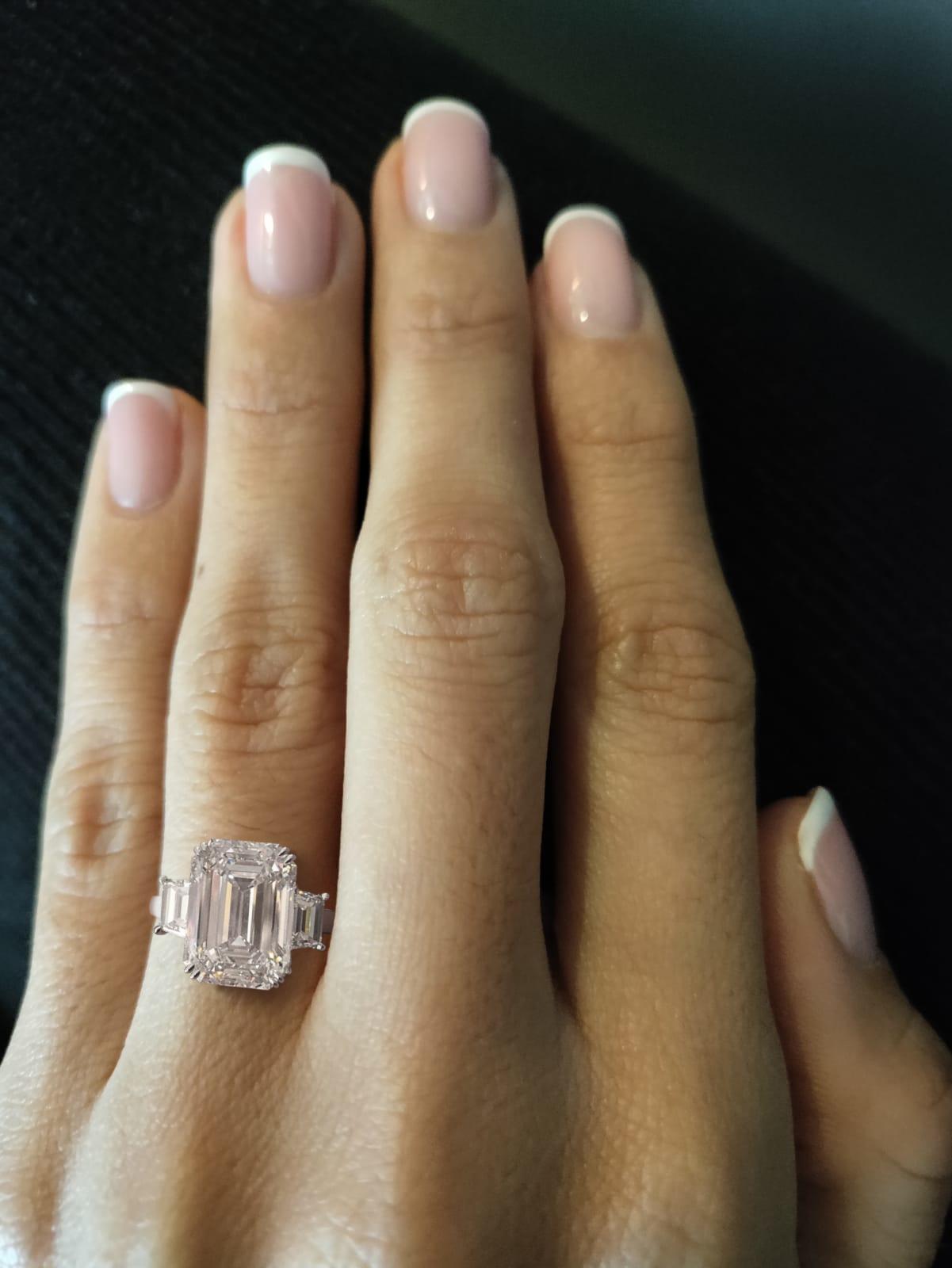 Platinum three stone emerald cut diamond engagement ring. Centering one fine quality emerald cut diamond weighing 6.25 carats.
Flanked by two trapezoid cut diamonds weighing a combined total of 0.75 carats. 
Diamond grading: color grade: J. Clarity