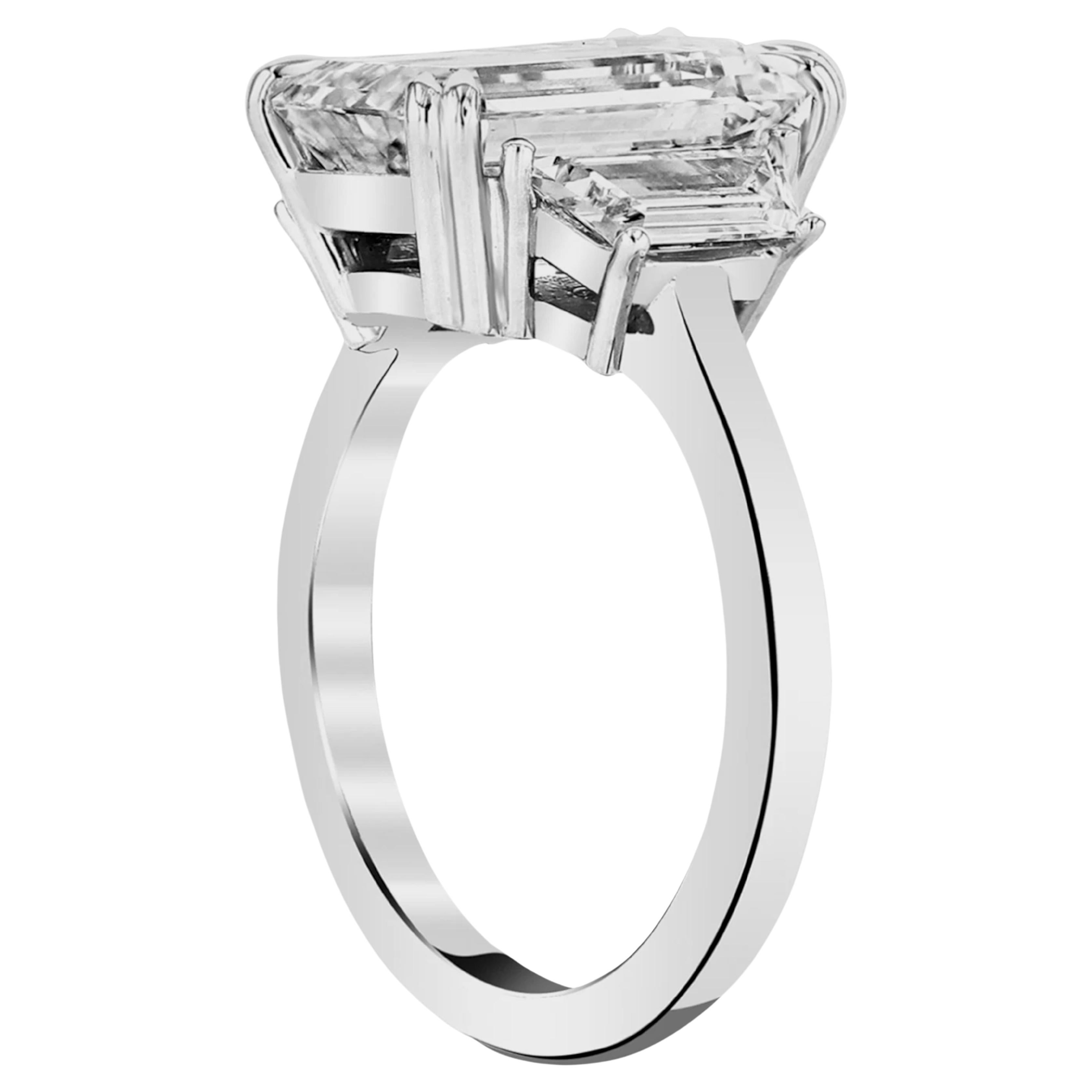 This extraordinary ring features a 5.03 carat emerald cut diamond as it's centerpiece, radiating sophistication and timeless elegance.  Flanked by trapezoid-shaped diamonds, the design achieves a harmonious and refined aesthetic. Set in platinum,