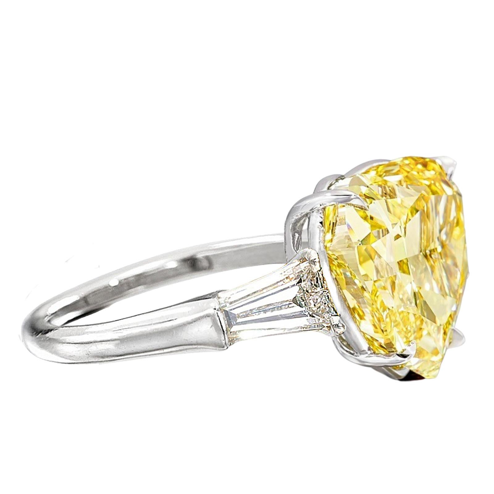 Questo squisito anello mette in mostra un diamante mozzafiato da 5 carati con taglio a cuore, certificato GIA, in un vibrante colore giallo fantasia che irradia calore e individualità. La rara forma a cuore, simbolo di amore e devozione, è