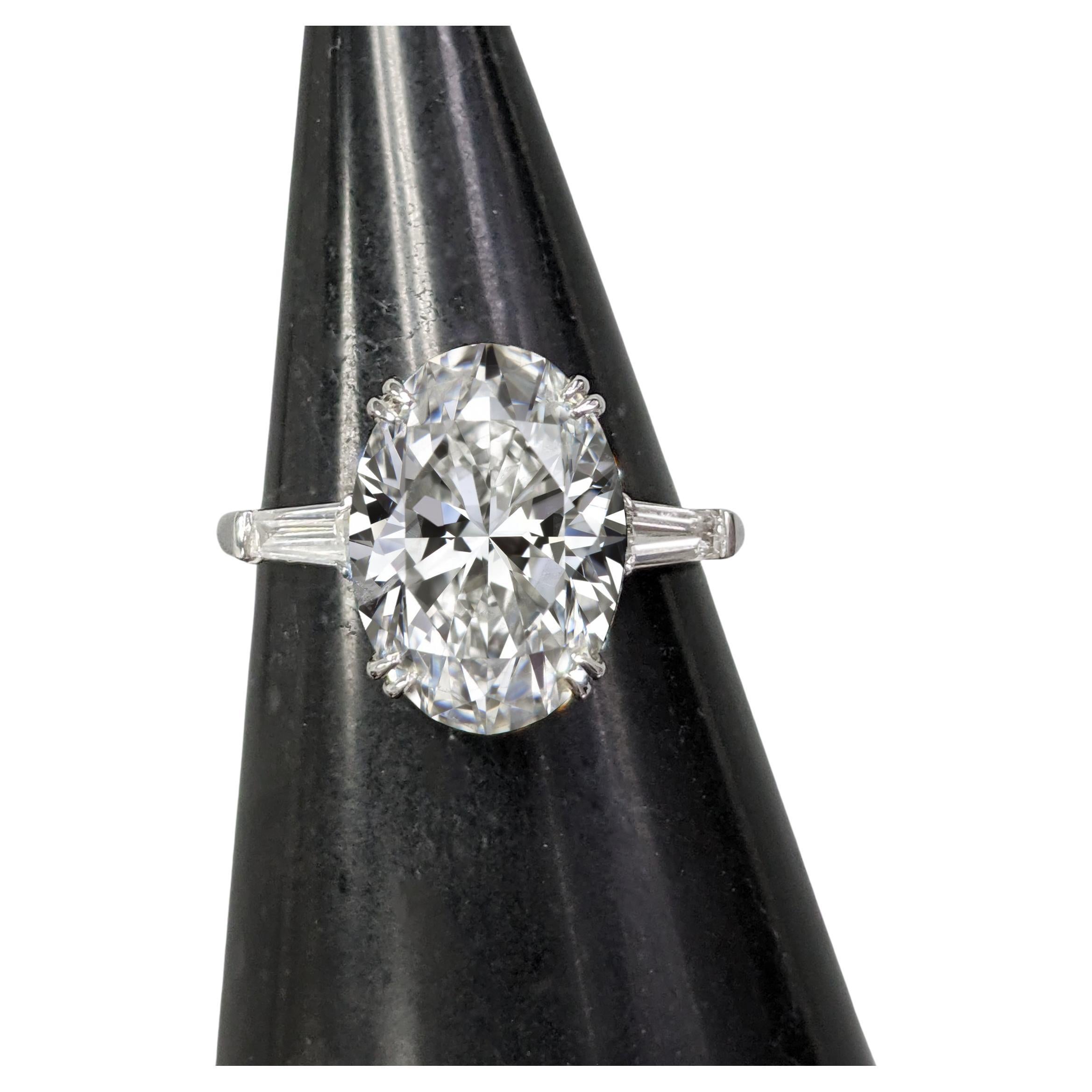 Questo anello mozzafiato presenta un diamante ovale da 4 carati certificato GIA, squisitamente incastonato in oro bianco 18 carati e affiancato da diamanti baguette affusolati su entrambi i lati. La perfetta integrazione di queste pietre laterali