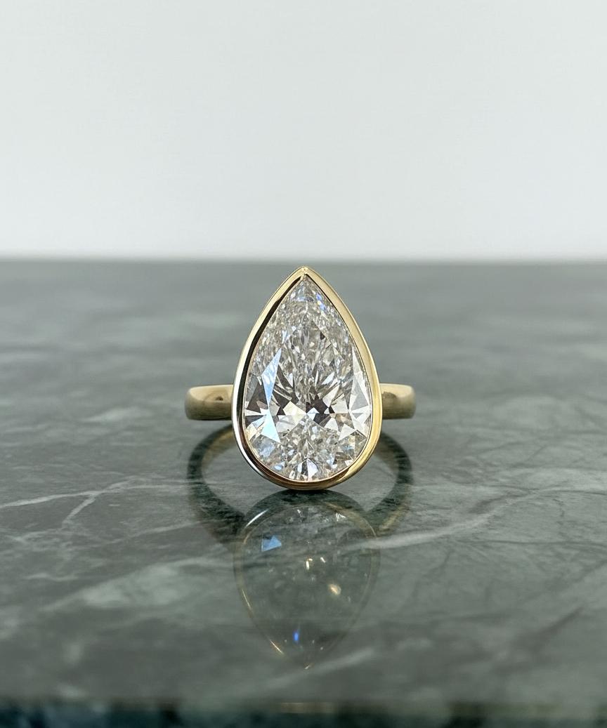 A timeless and elegant engagement or statement ring featuring a stunning GIA Certified 5 carat Pear Brilliant Cut Diamond, graded I color and VS2 clarity. This diamond displays exceptional brilliance and fire, beautifully accentuated by its refined