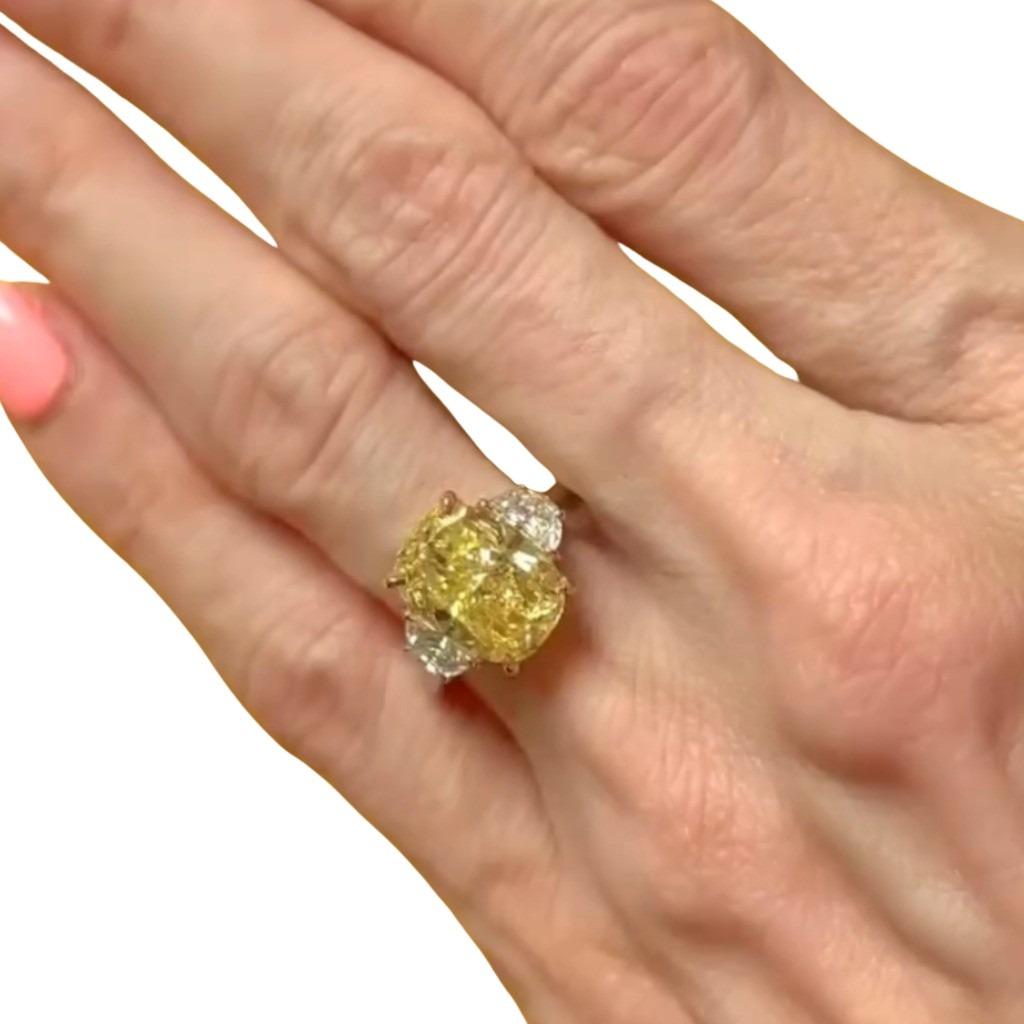 A striking and sophisticated cocktail ring showcasing a GIA certified 5.01 carat cushion modified brilliant cut diamond, graded Fancy Yellow color and SI1 clarity. The vibrant yellow diamond is securely set in an 18K yellow gold basket, which