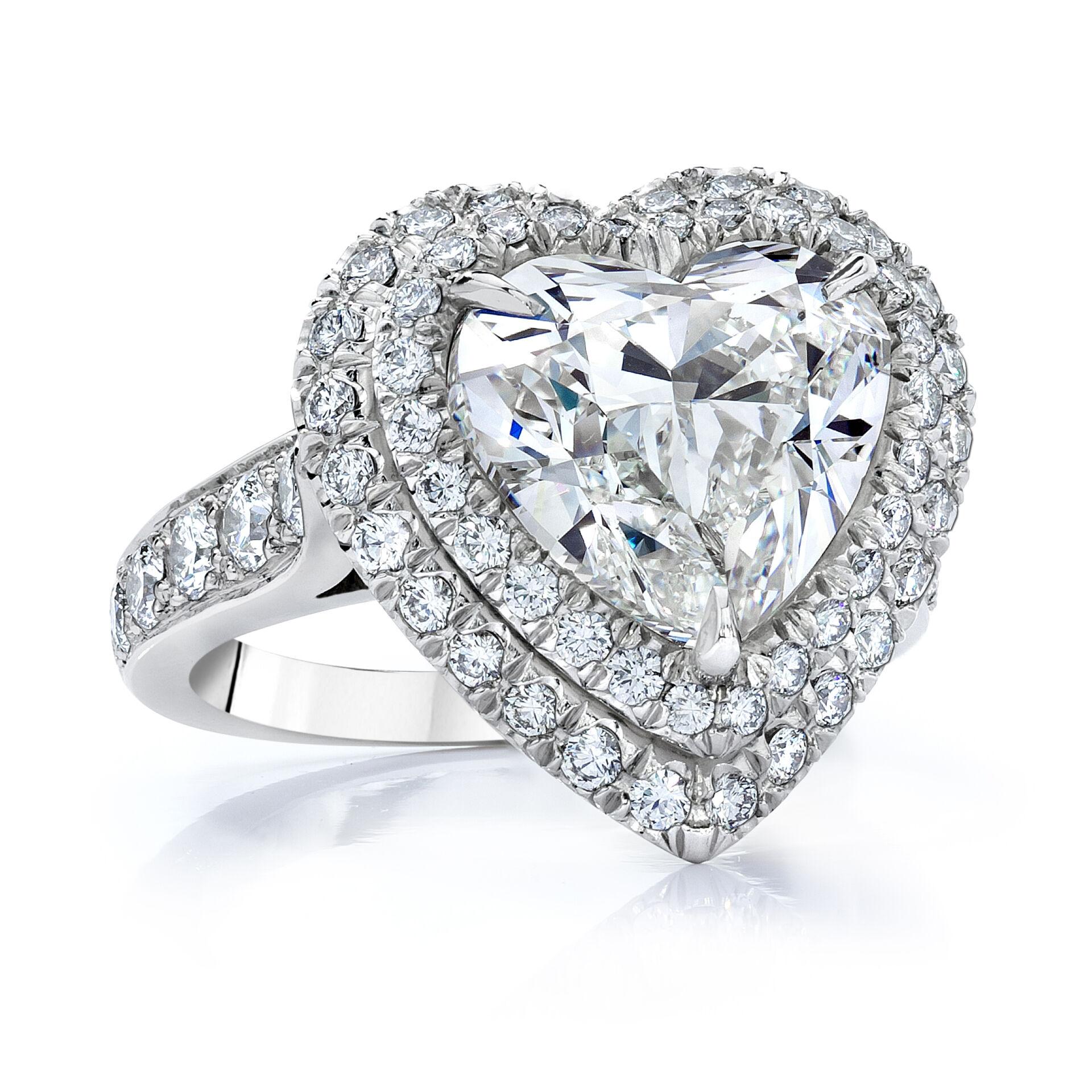 Une magnifique bague de fiançailles, mettant en valeur un impressionnant diamant en forme de cœur de 5,01 carats certifié par le GIA de couleur H et de pureté VS2, serti sur une monture à trois griffes. Elle est rehaussée d'un double halo et d'une