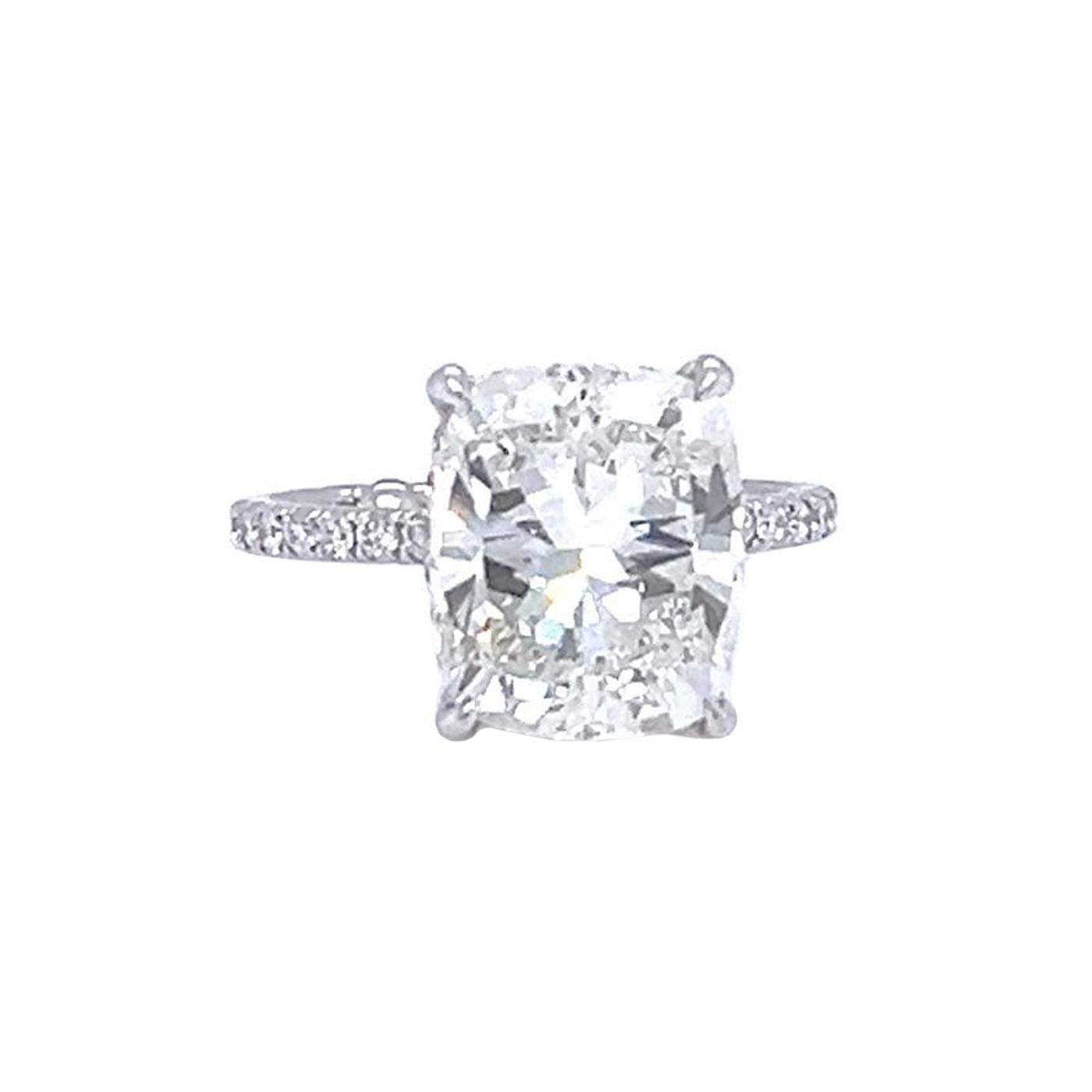 Ce diamant naturel de 5,01ct de taille coussin à couper le souffle est magnifiquement serti dans une bague à pavé de diamants en or blanc méticuleusement travaillée. La couleur J et la pureté VS2 du diamant garantissent son éclat, tandis que son