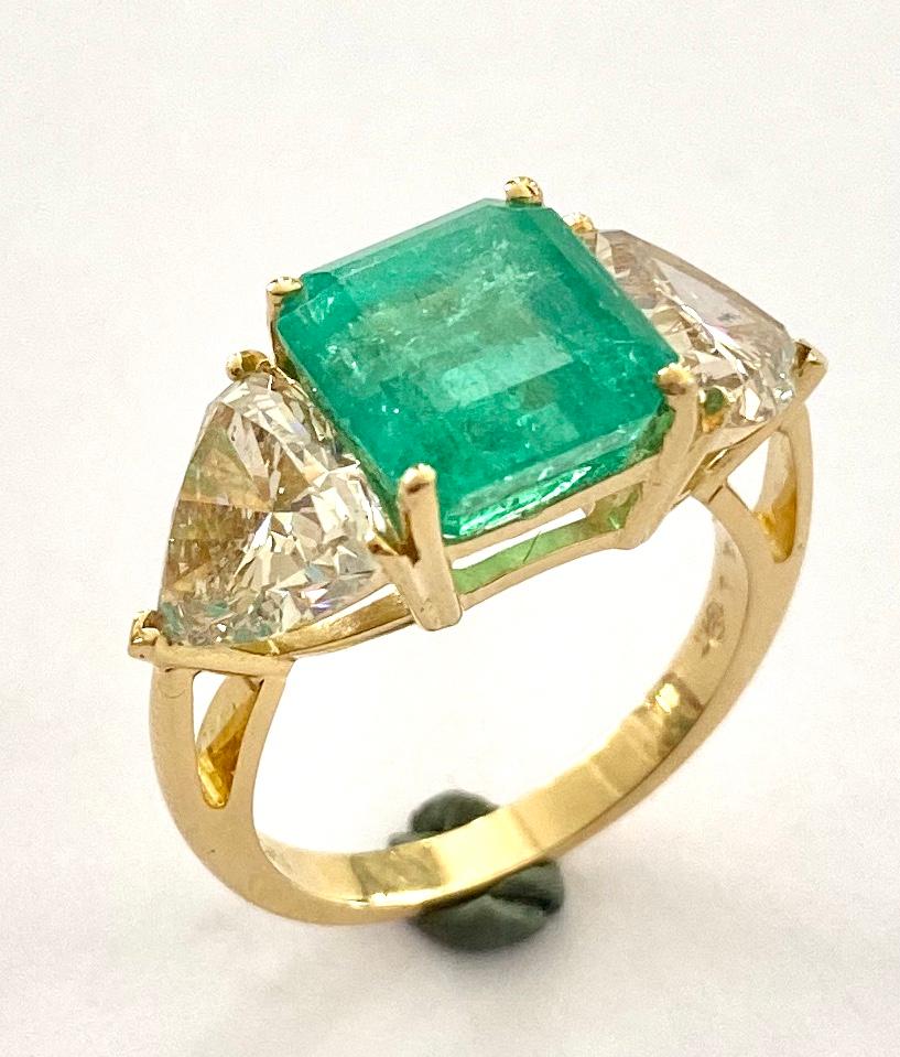 One (1) 18K. handmade ring in Yellowgold. set with:
One (1) Natural Beryl, variety: Emerald, Geographic Origin: Colombia treatment: Clarity Enhanced (F2)  GIA = 5.05ct  Emerald step Cut.
Two (2) natural Diamonds, shape and Cutting Style:  Modiefied
