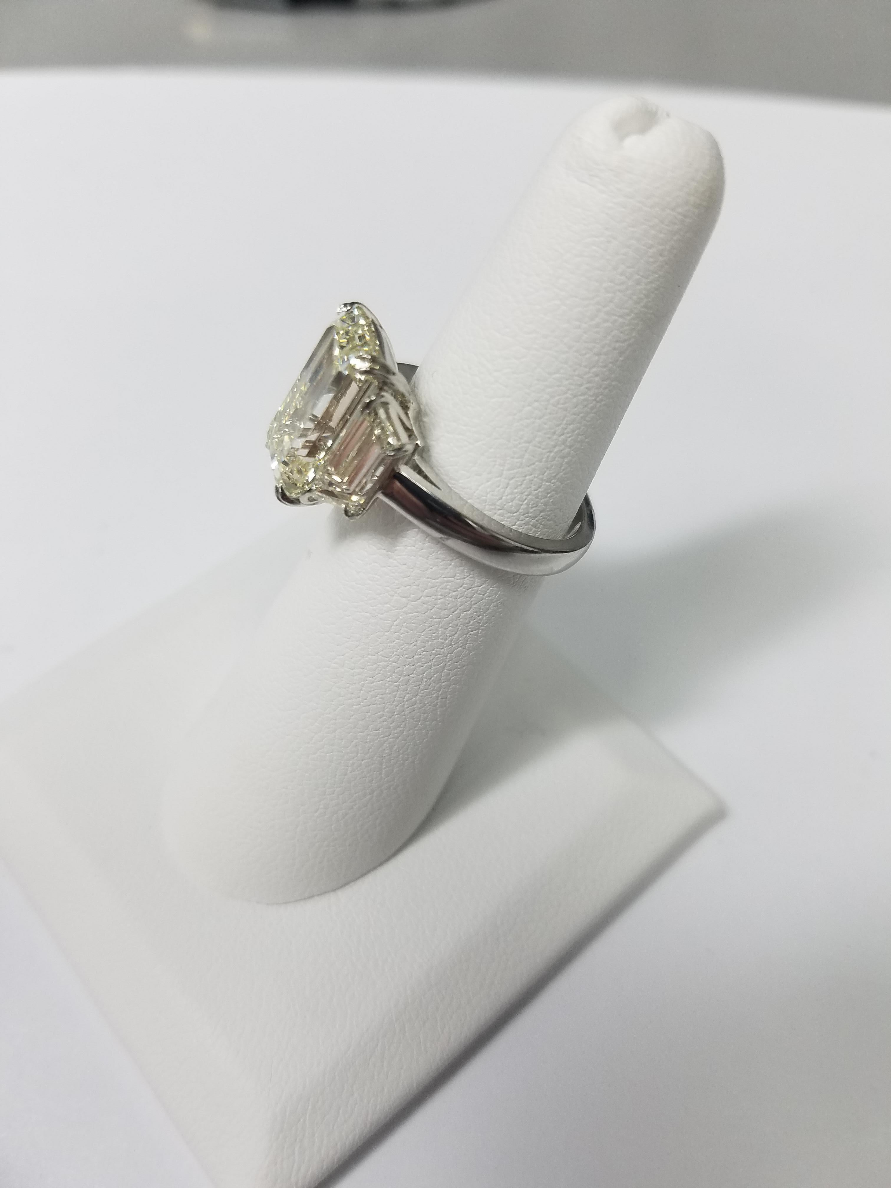 GIA Certified 5.11 carats Emerald Cut diamond ring. Center Stone is N color and VVS2 clarity. Set in a platinum setting with  2 trapezoid shaped diamonds weighing a total of 1.54 carats. 