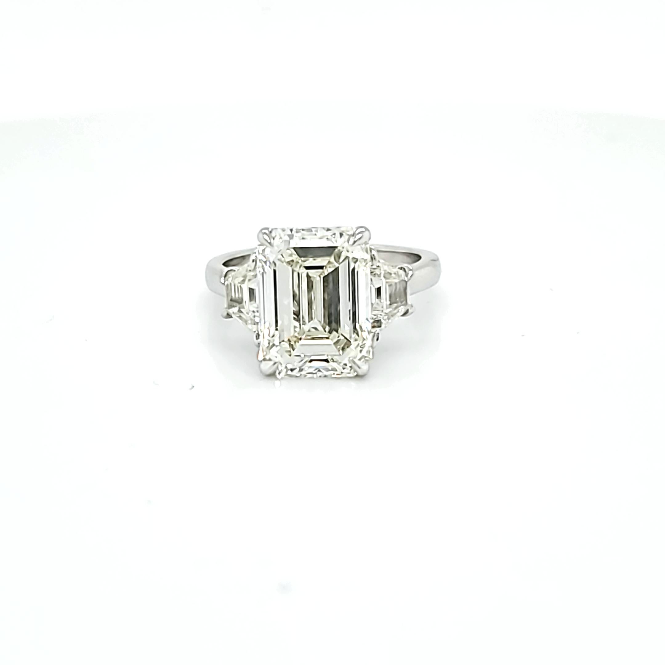 Center Stone is 5.12 carat Emerald Cut DIamond with an L color and VS1 clarity. Side stones are step cut trapezoid shaped diamonds weighing 0.91 carats total and a similar color and clarity to the center stone. Set in a platinum ring.This is an