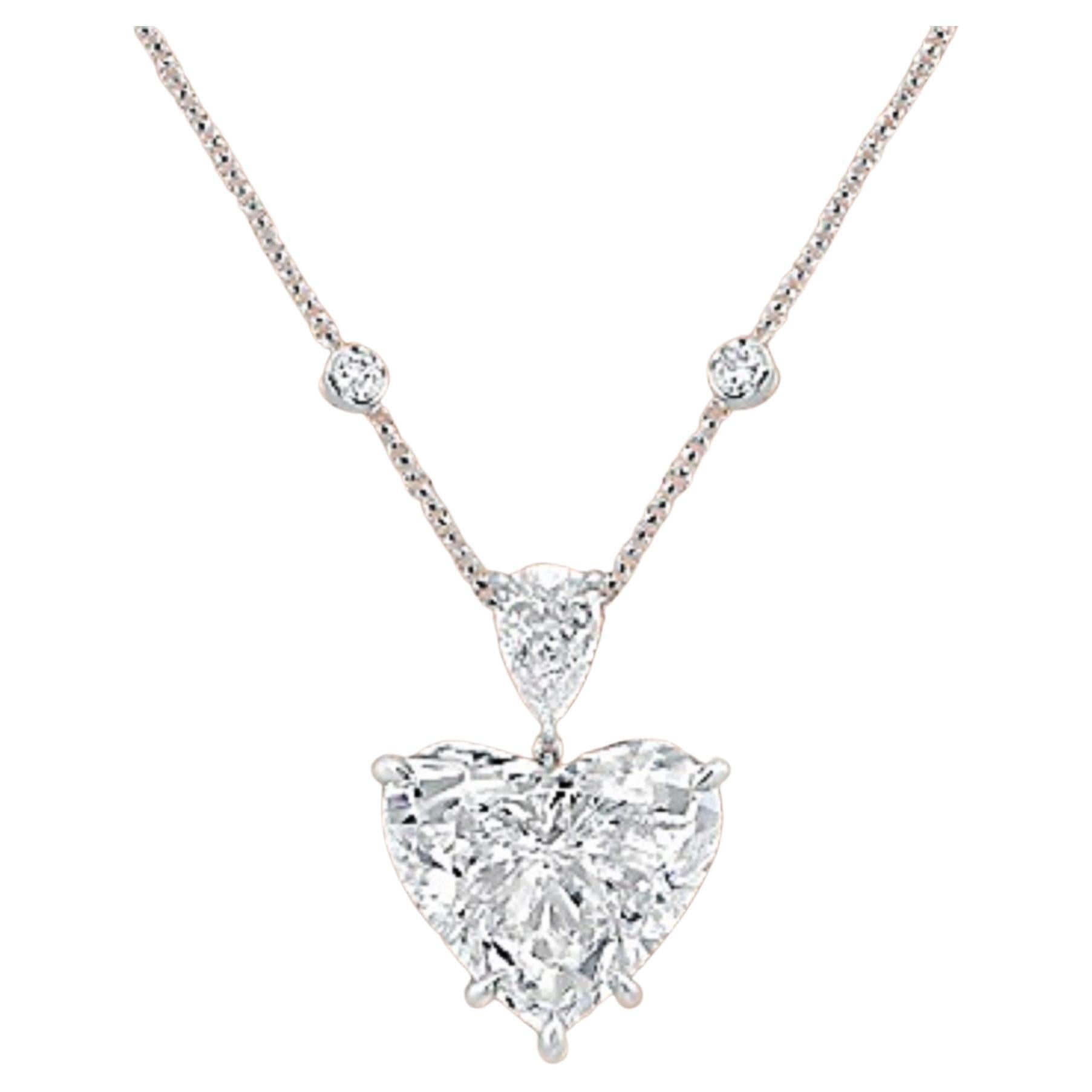 Ce collier pendentif exquis met en valeur un époustouflant diamant taillé en cœur de 5,40 carats comme pièce maîtresse, serti dans un luxueux or blanc 18 carats. 
Au-dessus du diamant en forme de cœur se trouve un éblouissant diamant taille poire
