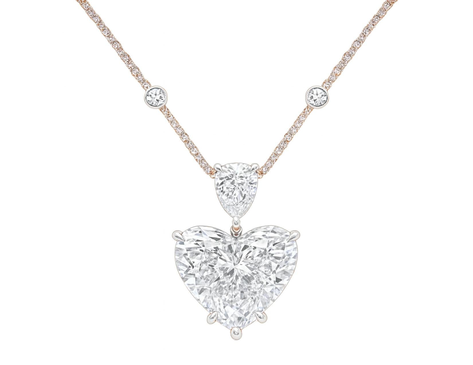 Ce collier pendentif exquis met en valeur un époustouflant diamant taillé en cœur de 5,40 carats comme pièce maîtresse, serti dans un luxueux or blanc 18 carats. 
Au-dessus du diamant en forme de cœur se trouve un éblouissant diamant taille poire
