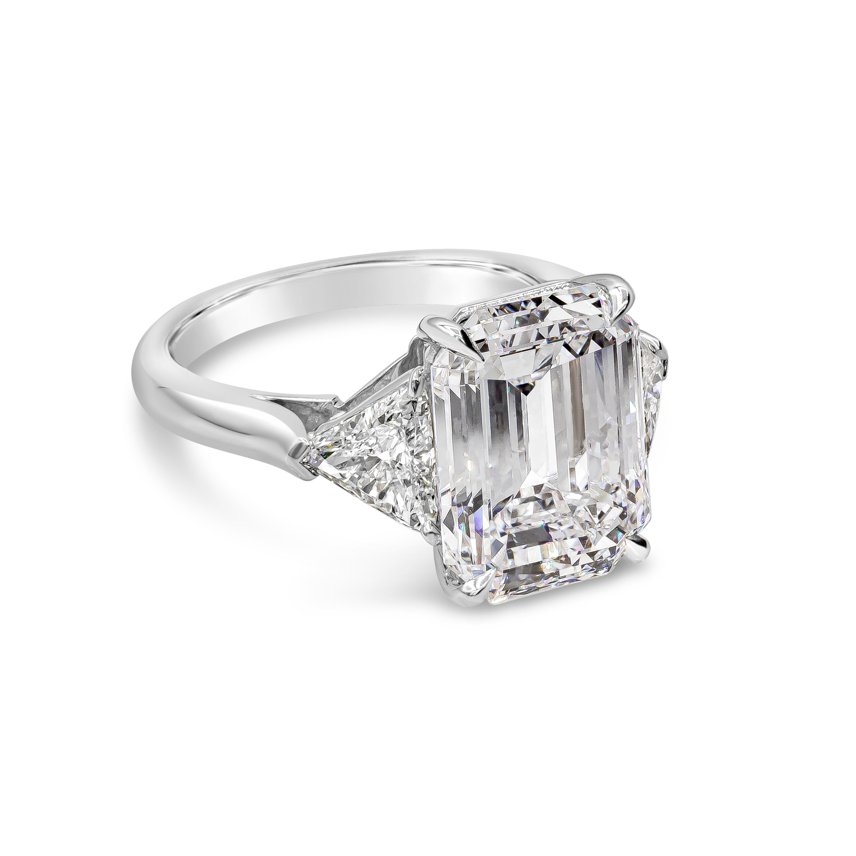 A classic and beautiful three-stone engagement ring showcasing a 5.46 carats emerald cut diamond, certified by GIA as F color and VS2 in clarity, set in four prong setting. Flanking the center are two brilliant trillion cut diamonds weighing 1.01