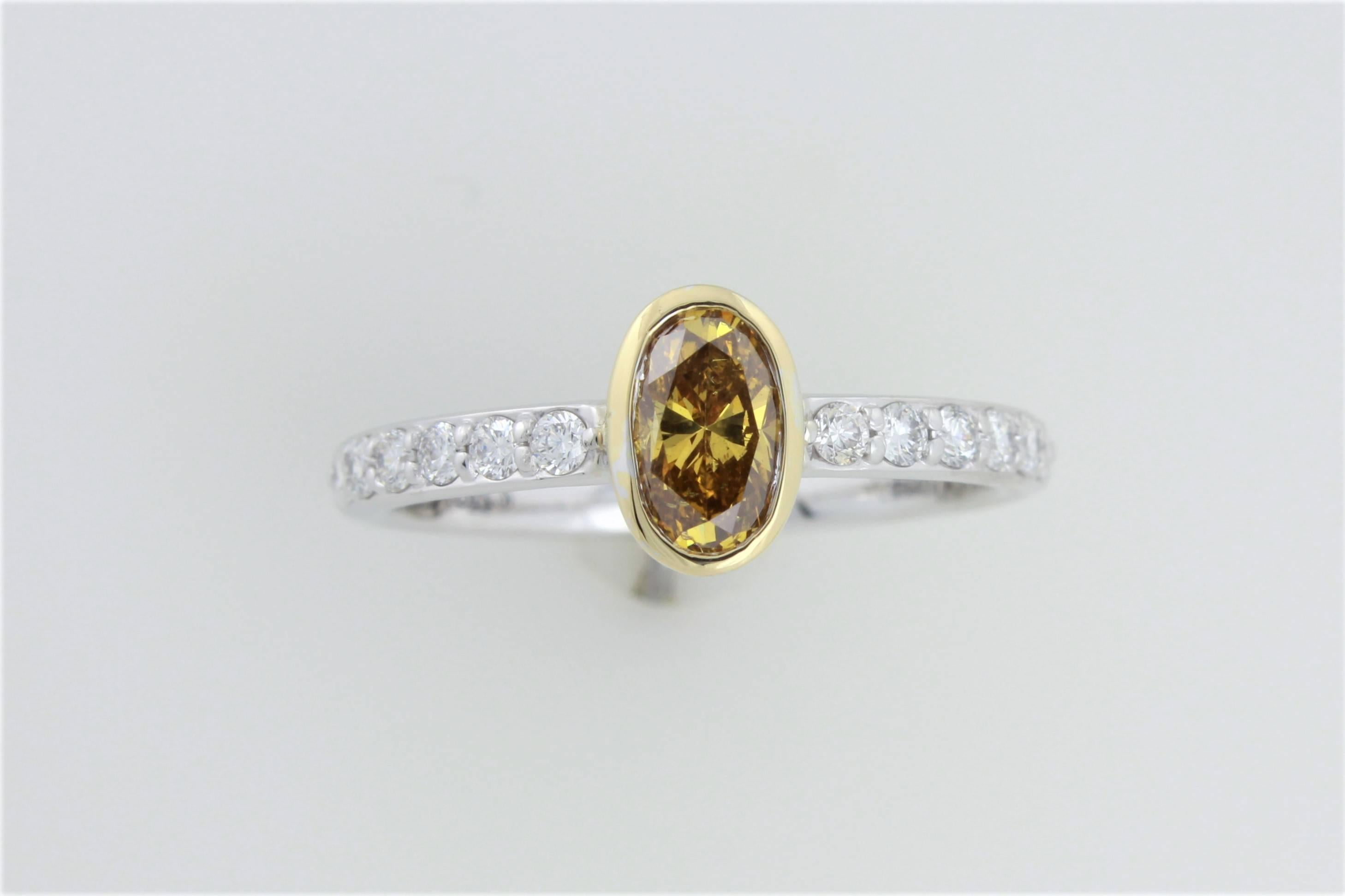 Presenting a stunning .56 carat, eye clean natural color Fancy Deep Orange Yellow oval diamond set in a classic 18 karat bezel in an 18 karat white gold and diamond ring!  The GIA lab report number is 15076980.  The white diamonds total .22 carats