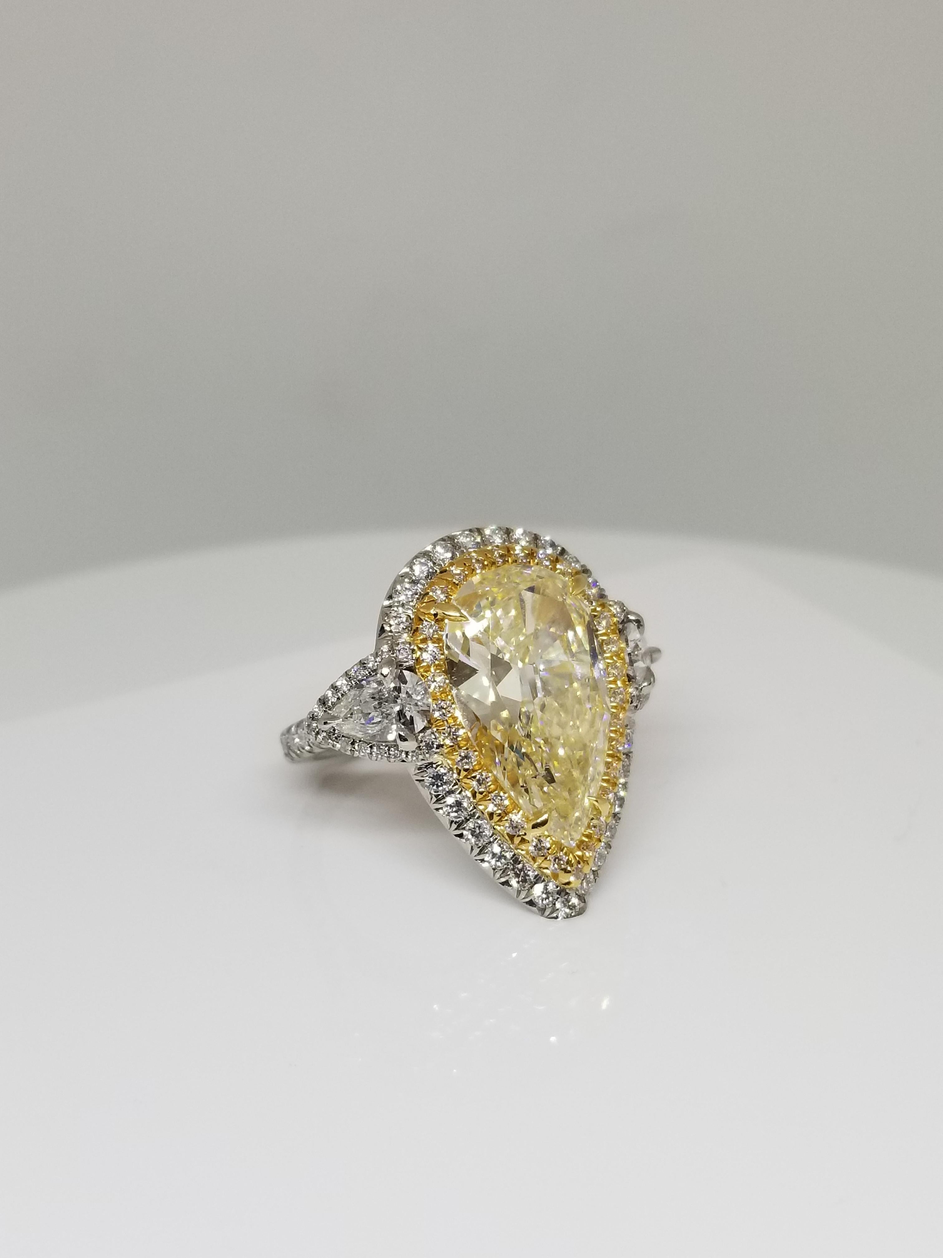Natural pear shape diamond weighing 5.66 carats by GIA 1176817540. Ring in platinum and 18 karats yellow gold; 3 rows design with 2 side pear shape diamonds mounted in double halo. Its transparency and luster are excellent.