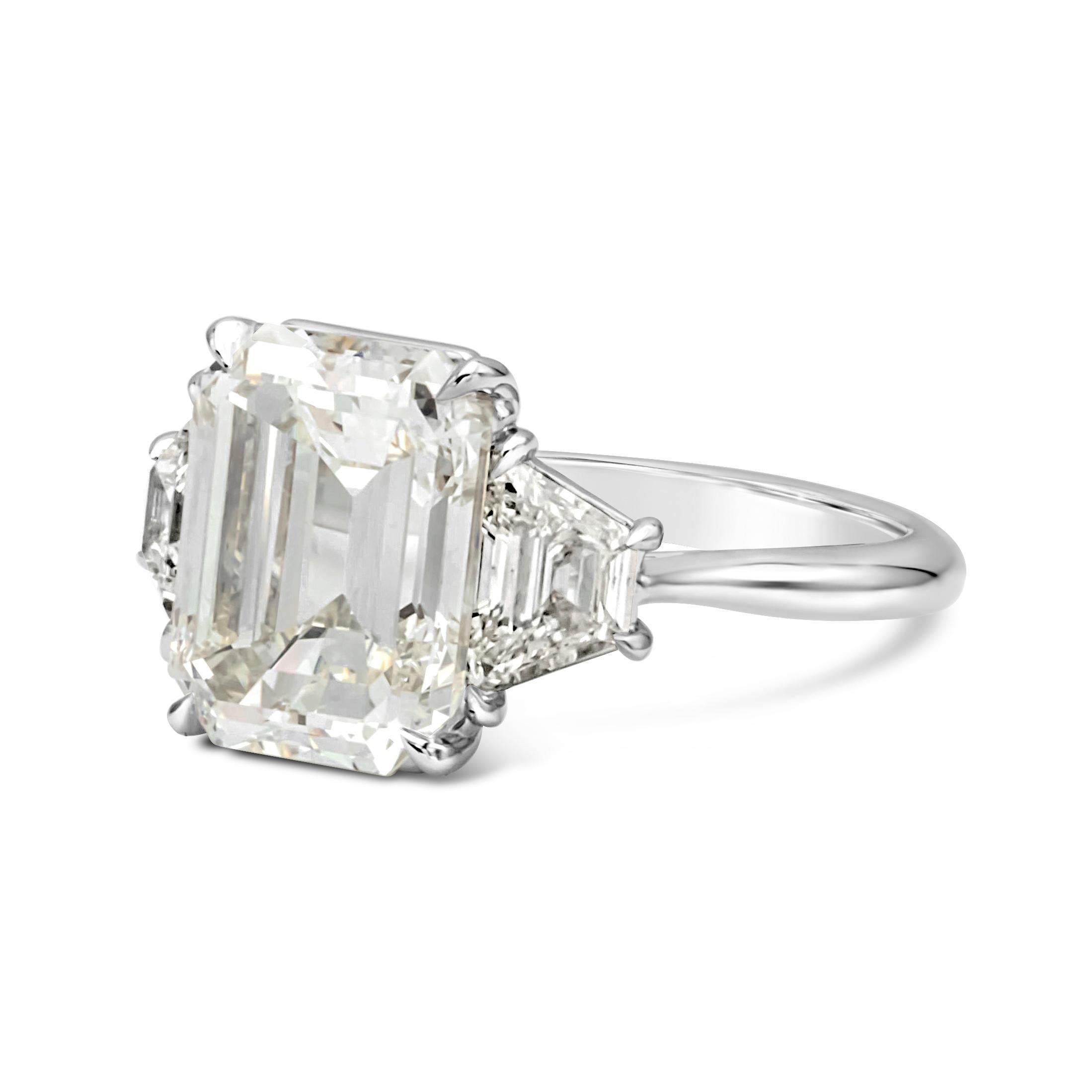 Elegantly made three stone engagement ring features a 5.81 carats emerald cut diamond certified by GIA as K color, VS2 in clarity, set in platinum four prong setting. Flanked by trillion cut diamonds on each side, weighing 1.10 carats total, J-K