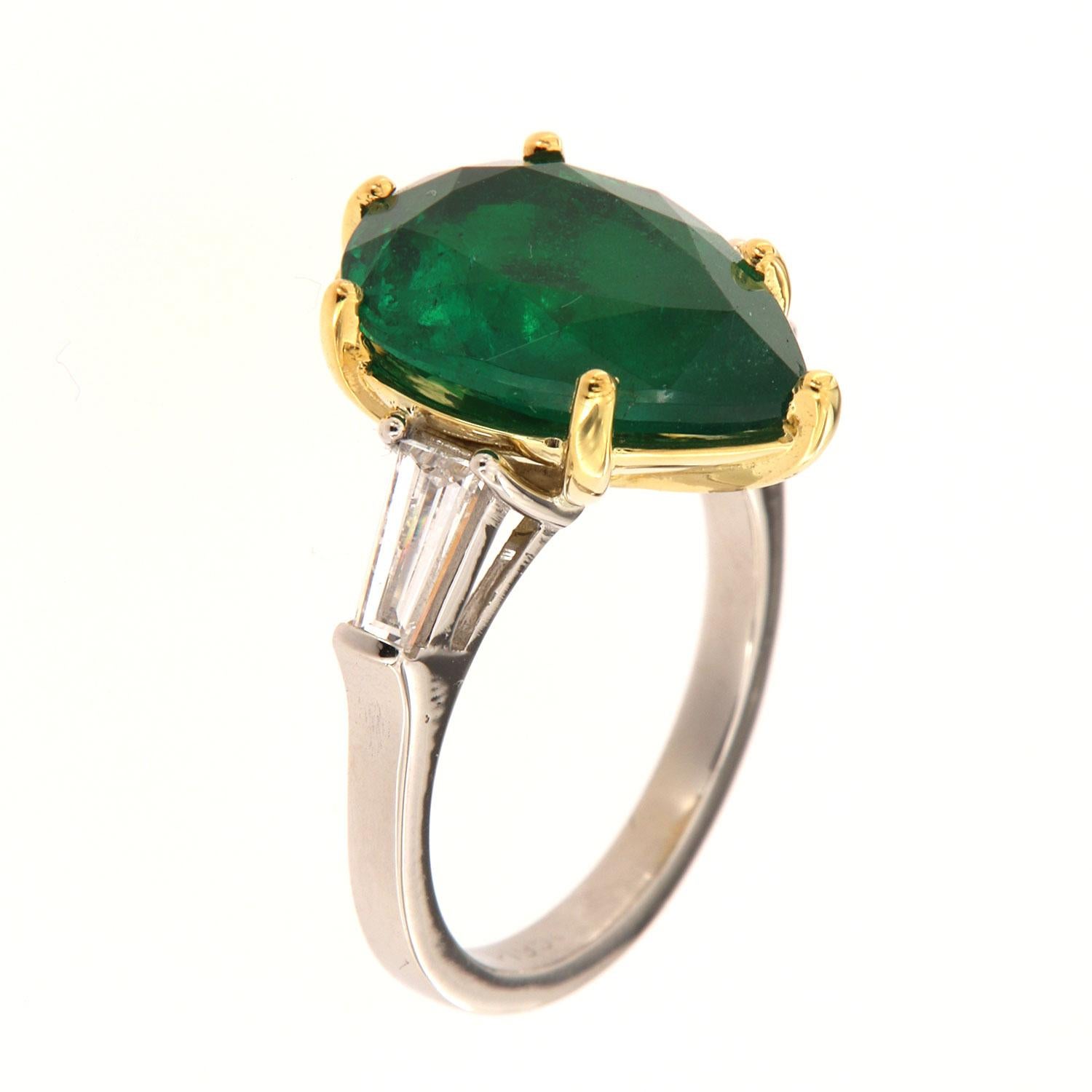 This Three-Stone Platinum and 18k yellow gold ring feature a 5.92 Carat Pear Shape bright, vibrant green Natural Emerald flanked by two (2) Baguettes on each side in a total weight of 0.57 Carat on a 2.1 mm wide band.
This Zambian Emerald exhibits a