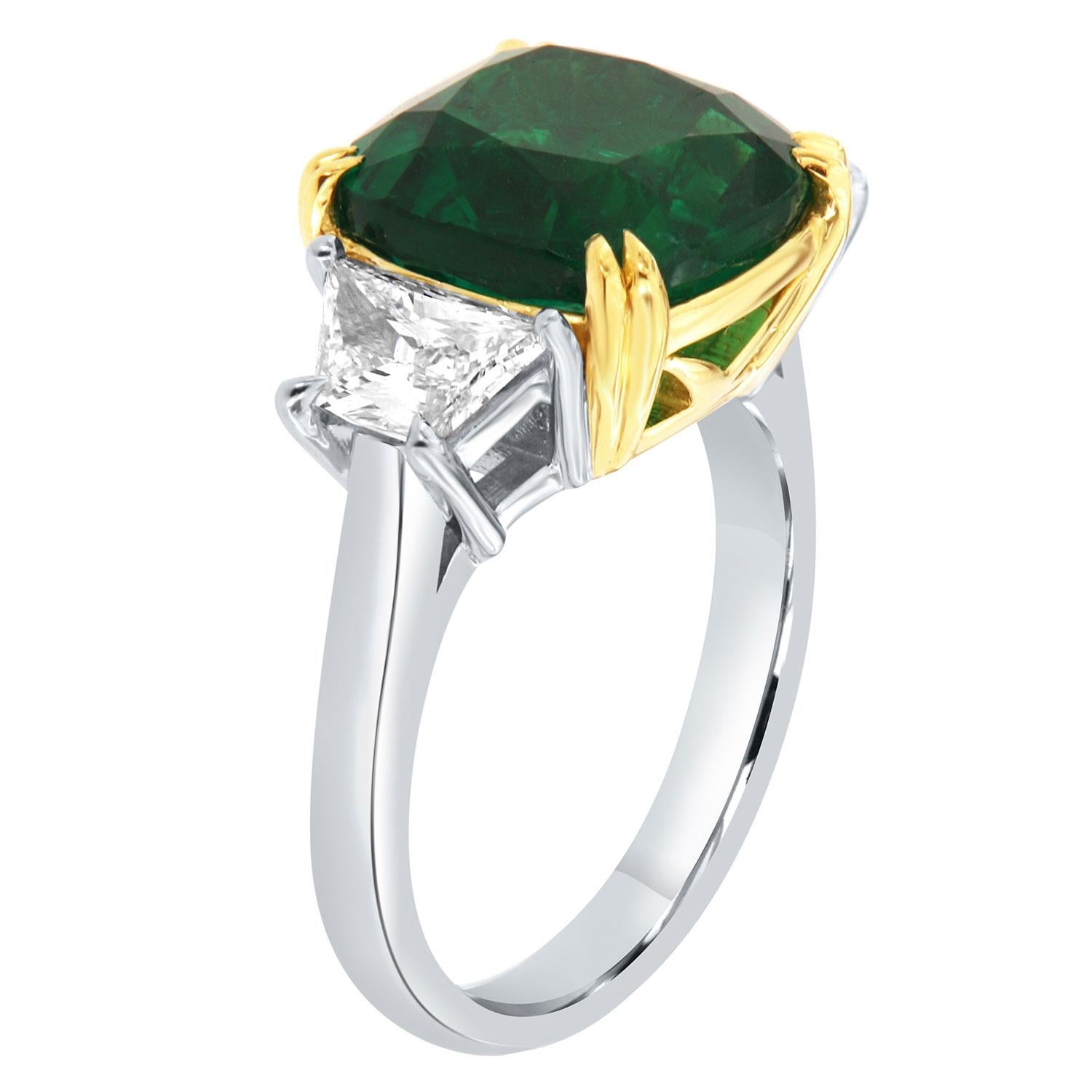 This one-of-a-kind three-stone Platinum ring features a Rare Natural 5.99 Carat Cushion Zambian Emerald flanked by two trapezoid shape diamonds in total weight of 1.08 Carat on a 2.6 mm wide band.  This extraordinary Emerald exhibits a vibrant green