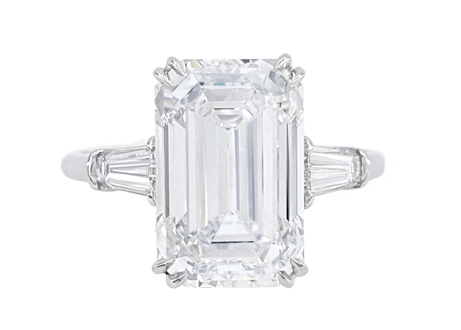 This resplendent ring showcases a magnificent 6-carat emerald-cut diamond, certified by the esteemed Gemological Institute of America (GIA) to guarantee its exceptional quality and authenticity. The diamond boasts an impeccable D color grade,
