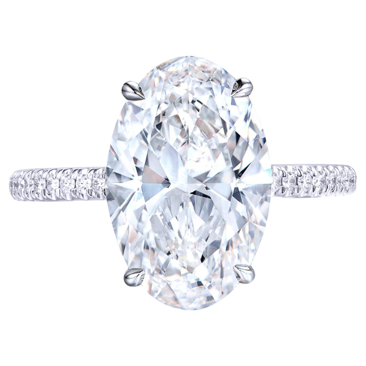 This refined engagement ring showcases a GIA certified 6 carat oval cut diamond, set in sleek platinum for a timeless solitaire design with added pavè detail. The elongated shape of the center stone enhances both finger coverage and brilliance,