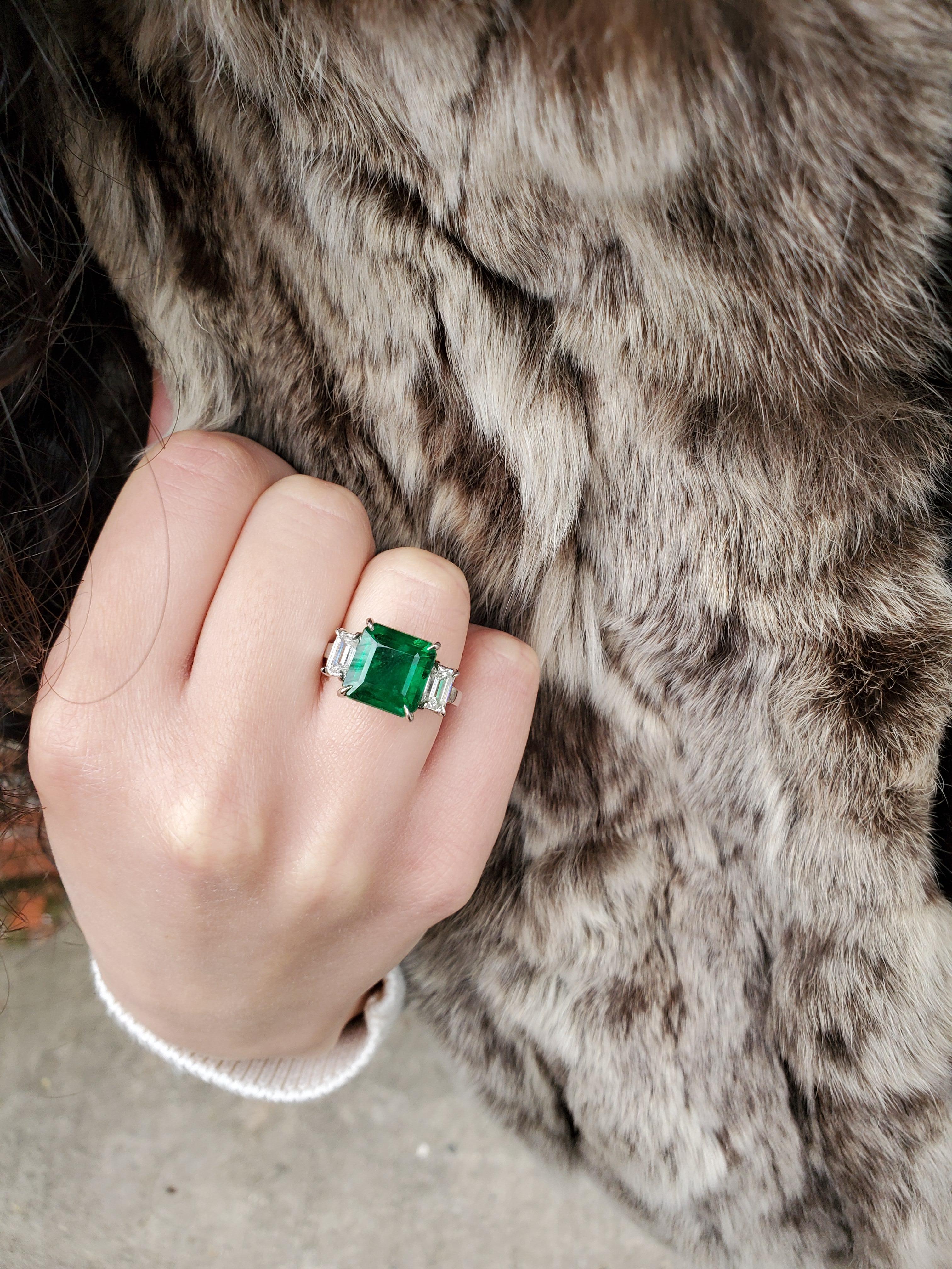 This stunning emerald and diamond three stone ring is remarkable. The platinum 3 stone genuine emerald and diamond ring has a GIA certified emerald gemstone set in a four prong setting. The prongs are pointed prongs (or claw prongs) that hold the