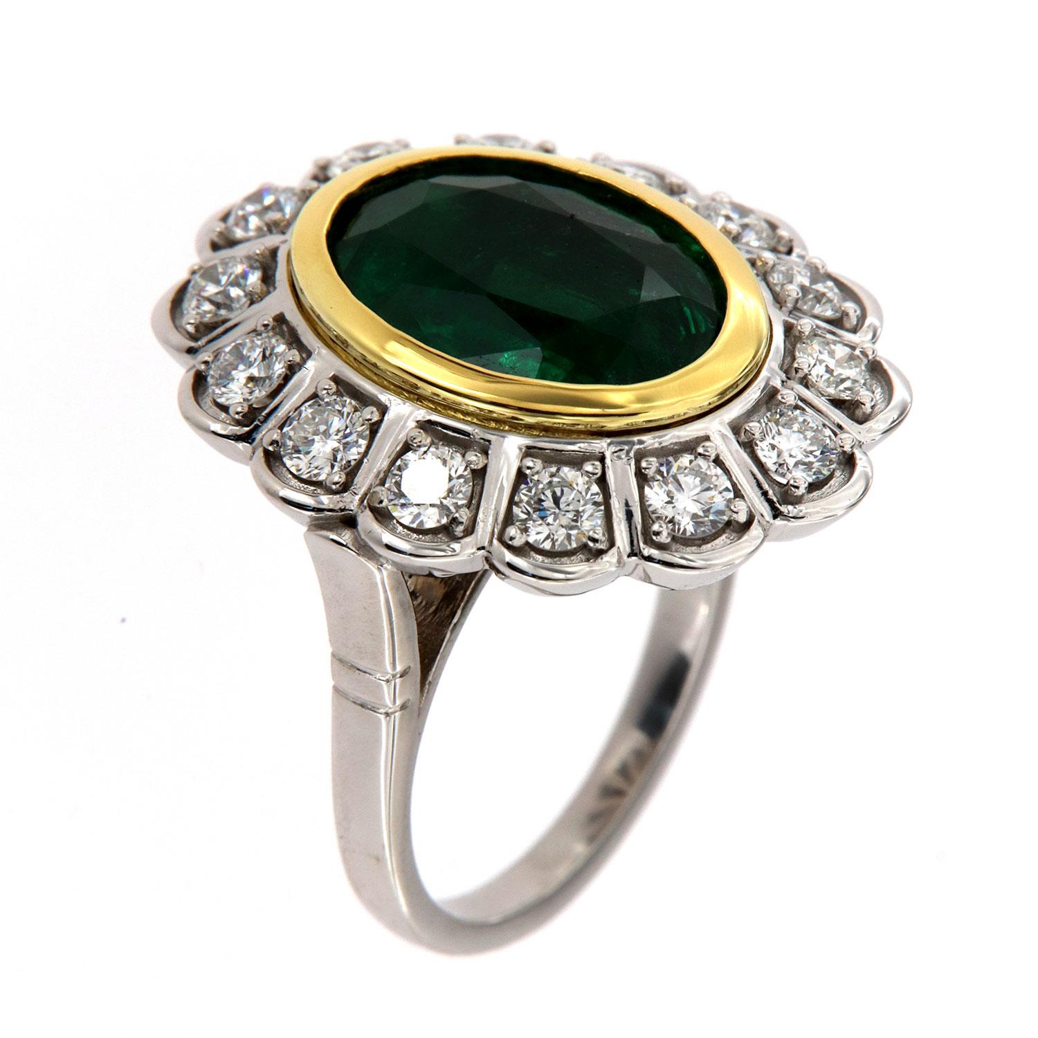 This stunning 18K White Gold Victorian-style ring features a 6.00 Carat GIA certified Zambian vibrant green emerald bezel set in 18k Yellow Gold. The emerald is surrounded by fourteen (14) Perfectly matched brilliant round diamonds in a total weight