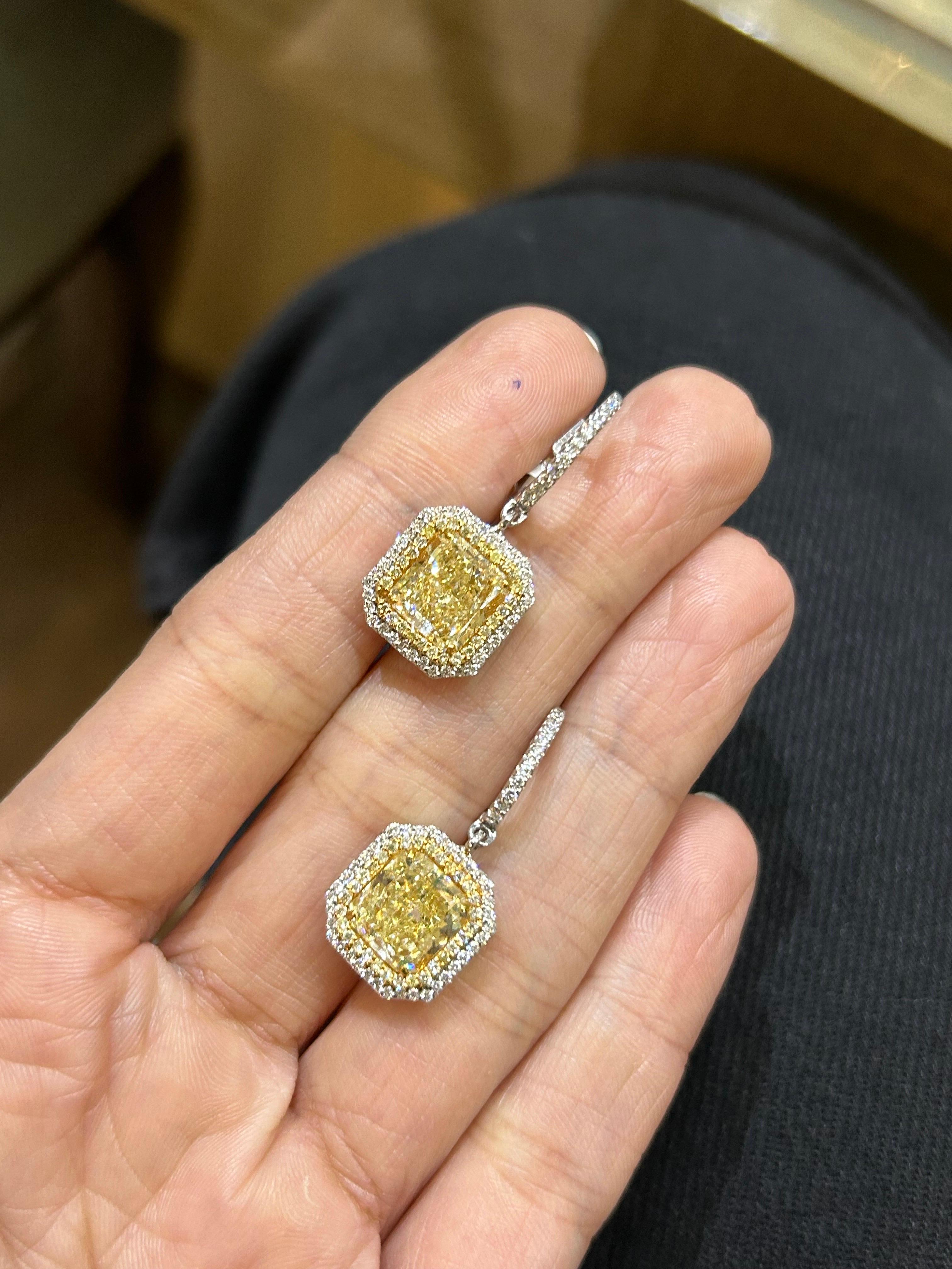 A classic pair of 3.01 and 3.00 carat Yellow Diamond dangle earrings, natural fancy light yellow in color, VVS1 and VVS2 quality. Surrounded by 0.82 carats of Yellow and White Diamonds. 
