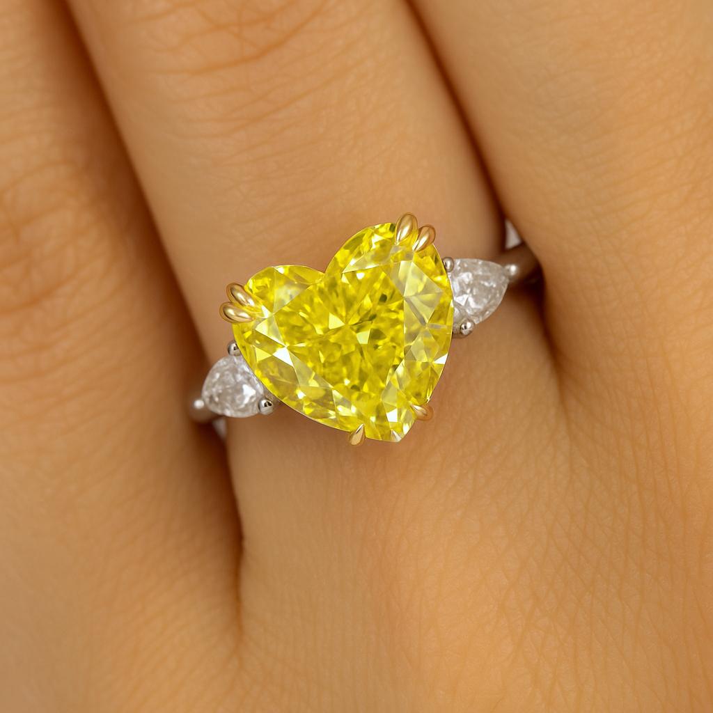 Extraordinaire déclaration d'élégance et de romantisme, cette bague sur mesure est ornée d'un diamant en forme de cœur de 6,02 carats certifié par le GIA, de couleur jaune fantaisie, d'une pureté irréprochable à l'intérieur, d'origine naturelle et