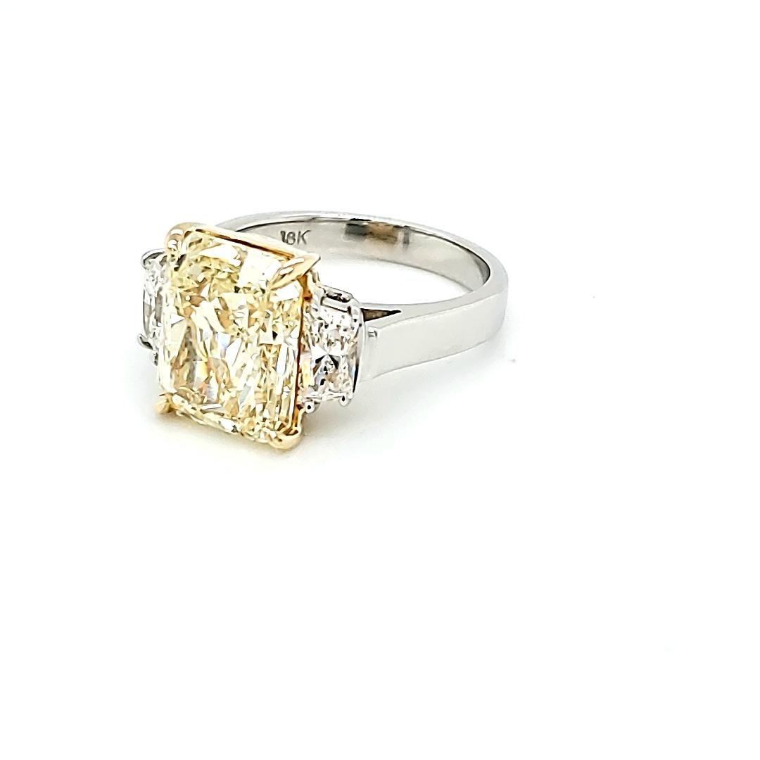 Center stone is a GIA certified 6.02 carat Fancy yellow Radiant Cut. VVS2 Clarity. Set in a handmade platinum and 18k yellow Gold ring with Brialliant Cut Trapezoid Diamonds weighing 0.79 carats total. 