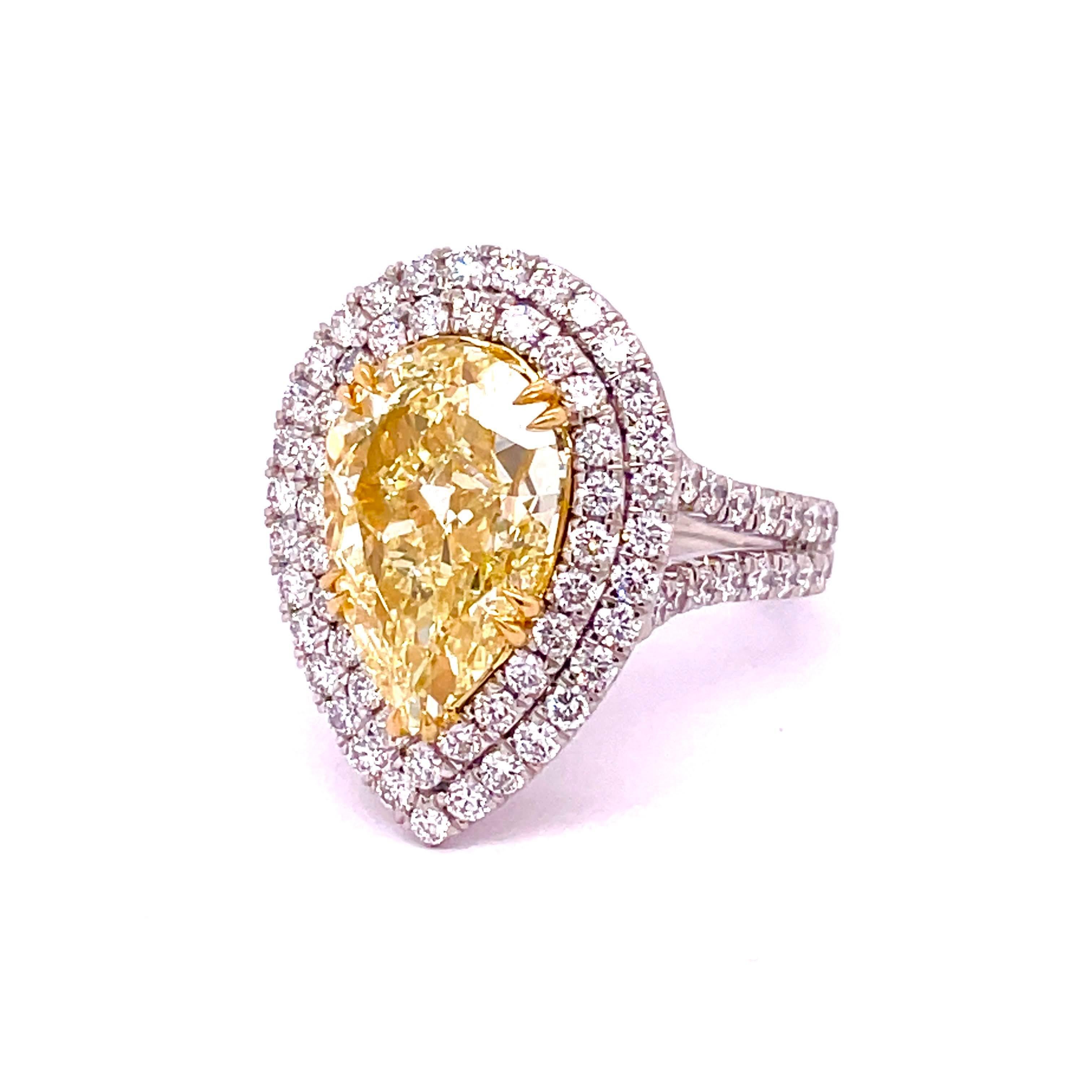 GIA Certified Pear Shape Diamond 6.02, Fancy Yellow Color VS2 Clarity mounted flawlessly on a 18K Yellow basket with claw prongs bringing out more vibrancy to the center diamond. Surrounded by 2.11 carat round diamonds for the double halo and split