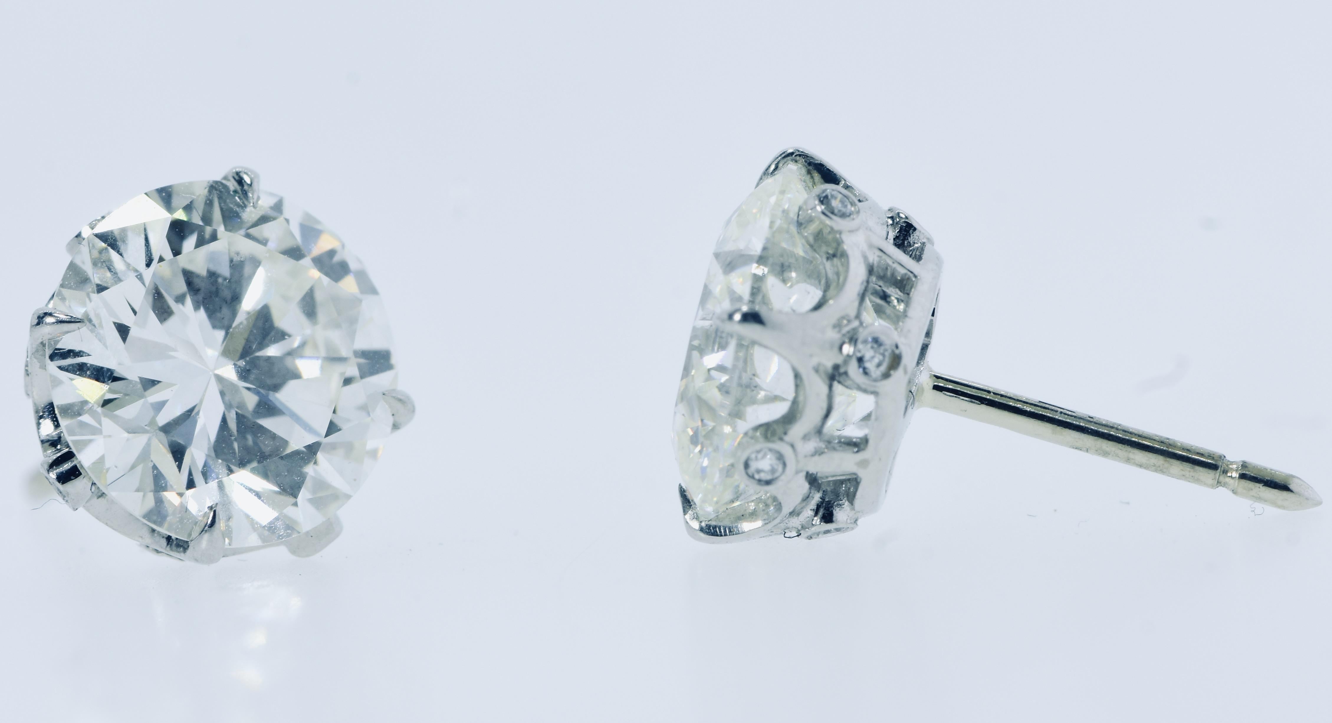 A pair of fine large round brilliant cut diamond stud earrings.  Graded by G.I.A. and hand crafted by Pierre/Famille in 8 prong platinum and tiny diamond crown like mountings, these two well matched diamonds weigh totally 6.11 cts., (3.03 and 3.08