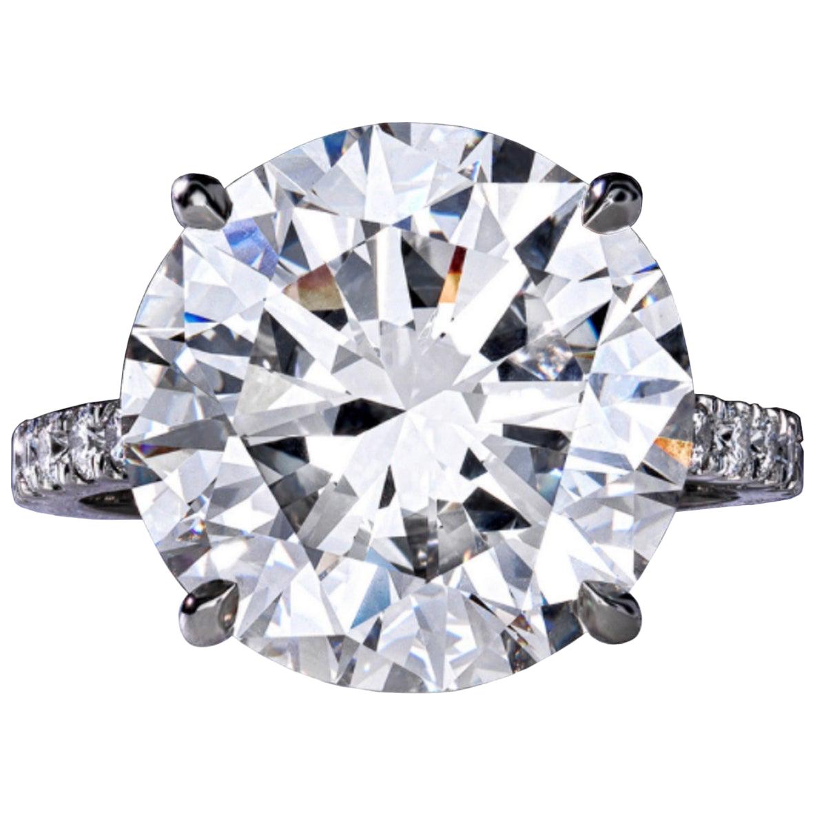 This exceptional engagement ring features a breathtaking 6.13 carat round brilliant cut diamond, set in a solitaire design with a delicate pavé of diamonds adorning the platinum band. 

The central diamond boasts a color grade of D, offering a